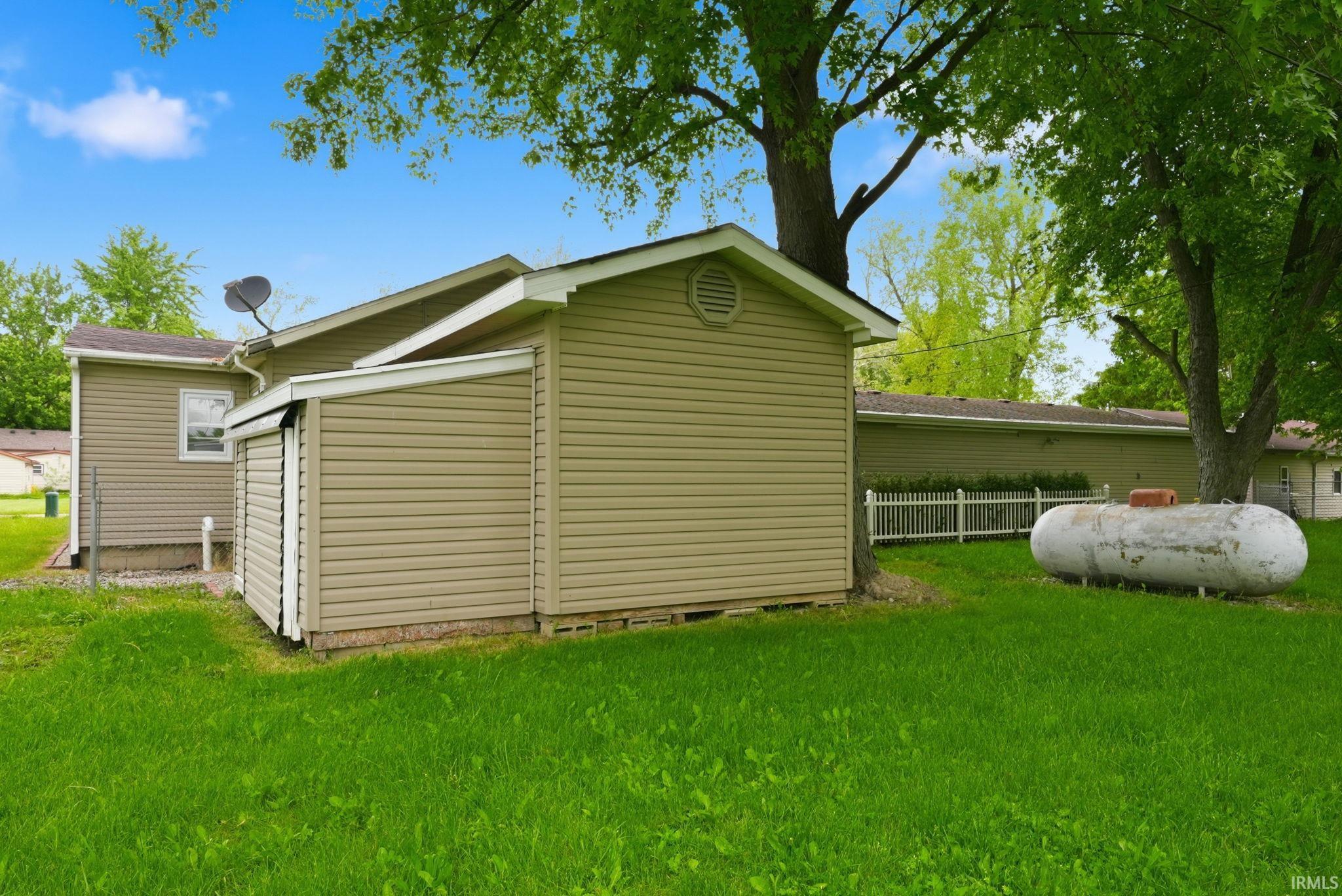 Side exterior with tan vinyl siding and a white picket fence