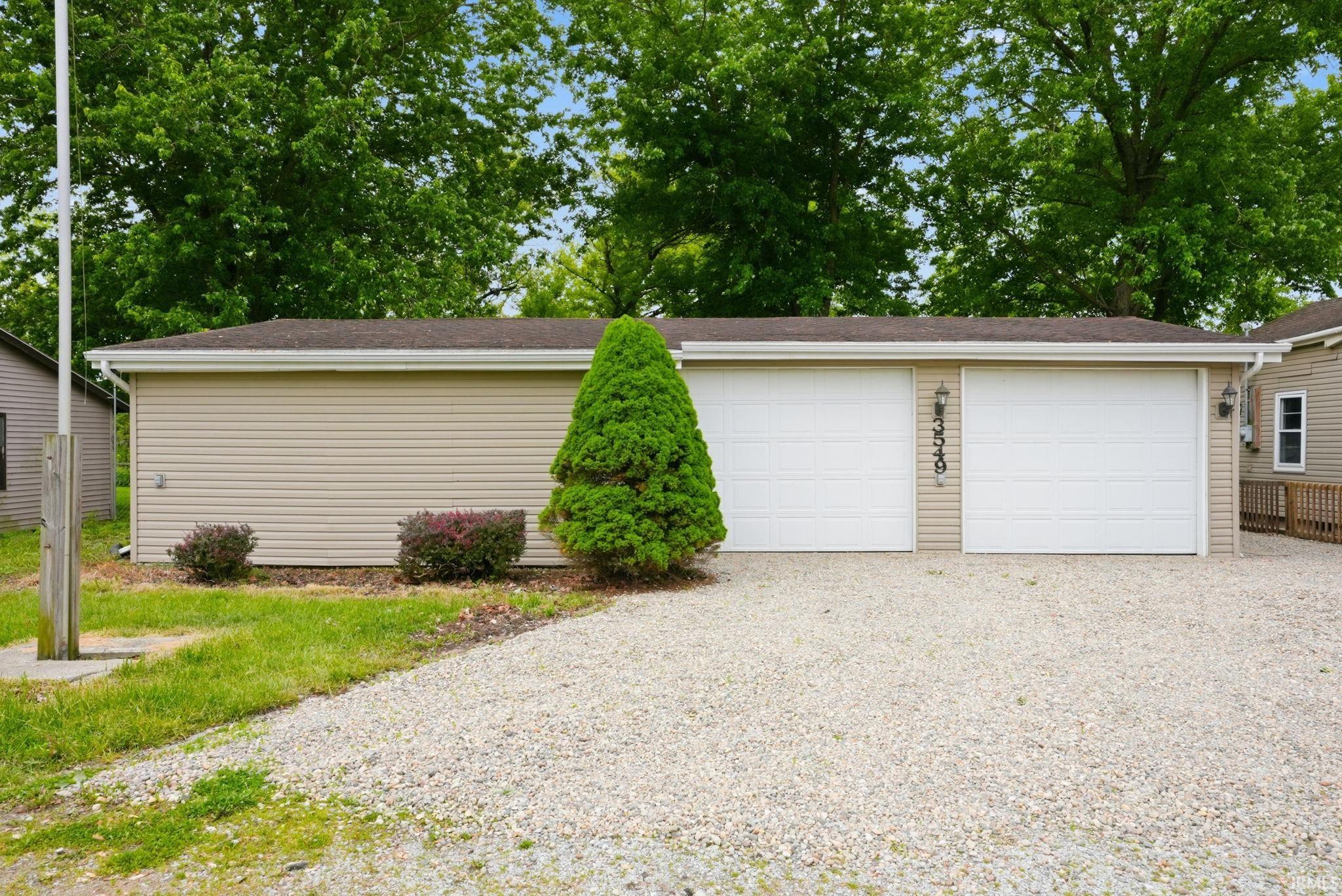 Two-car garage featuring white paneled doors and tan vinyl siding