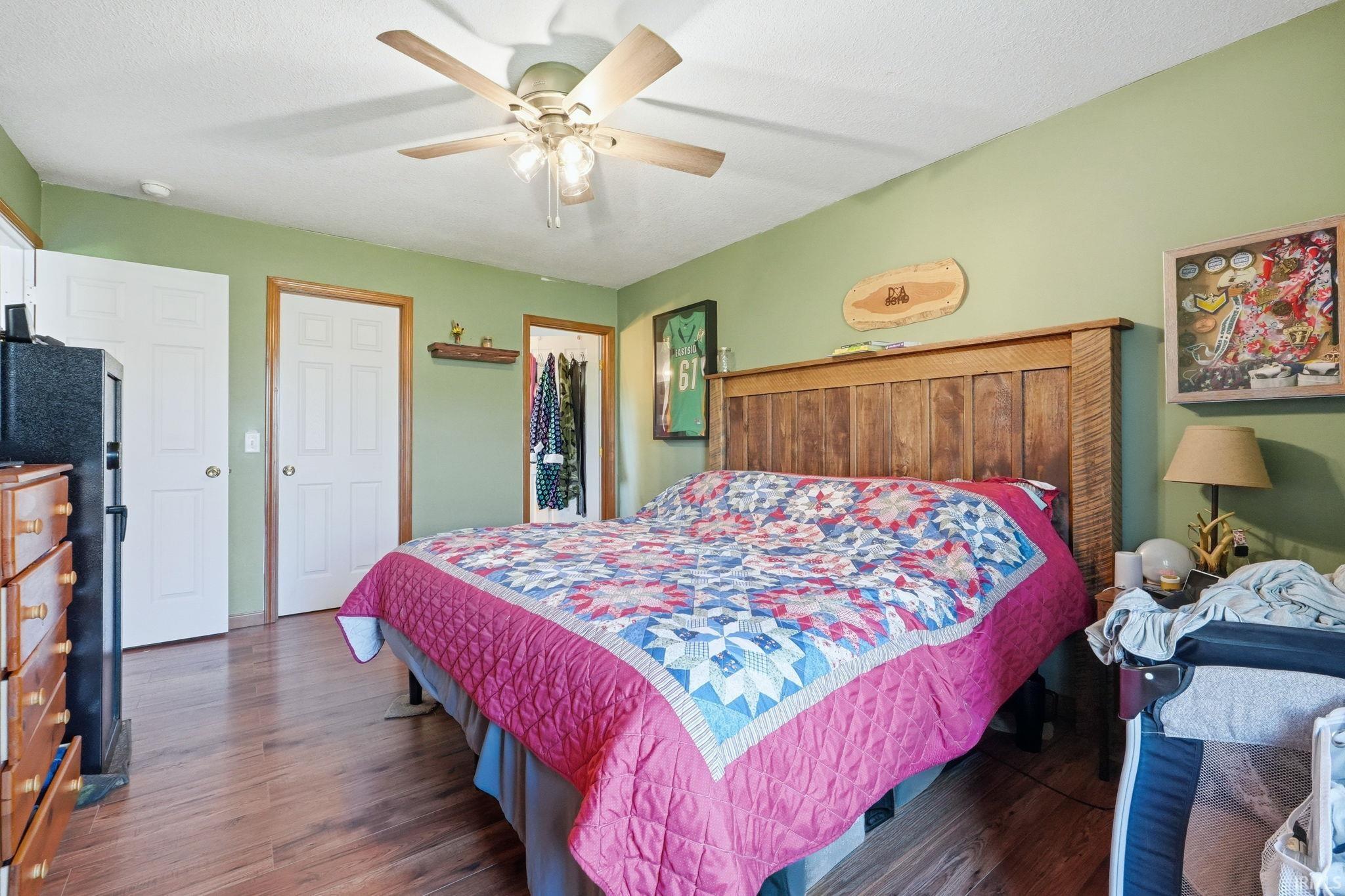 Spacious room featuring wood-finish flooring, light green walls, a ceiling fan, and white paneled doors