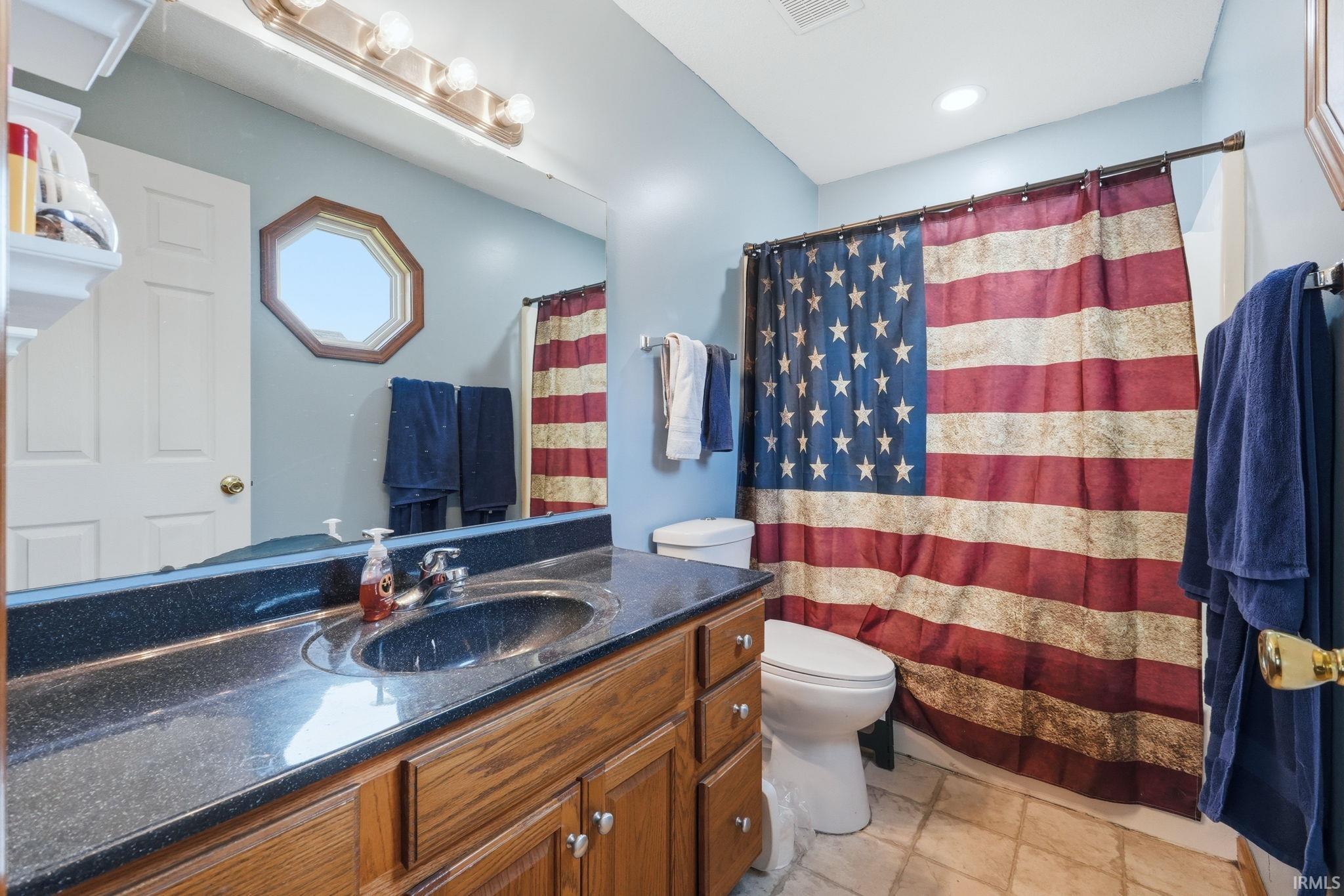 Bathroom featuring a dark countertop vanity with an undermount sink, overhead vanity lighting, and a framed mirror