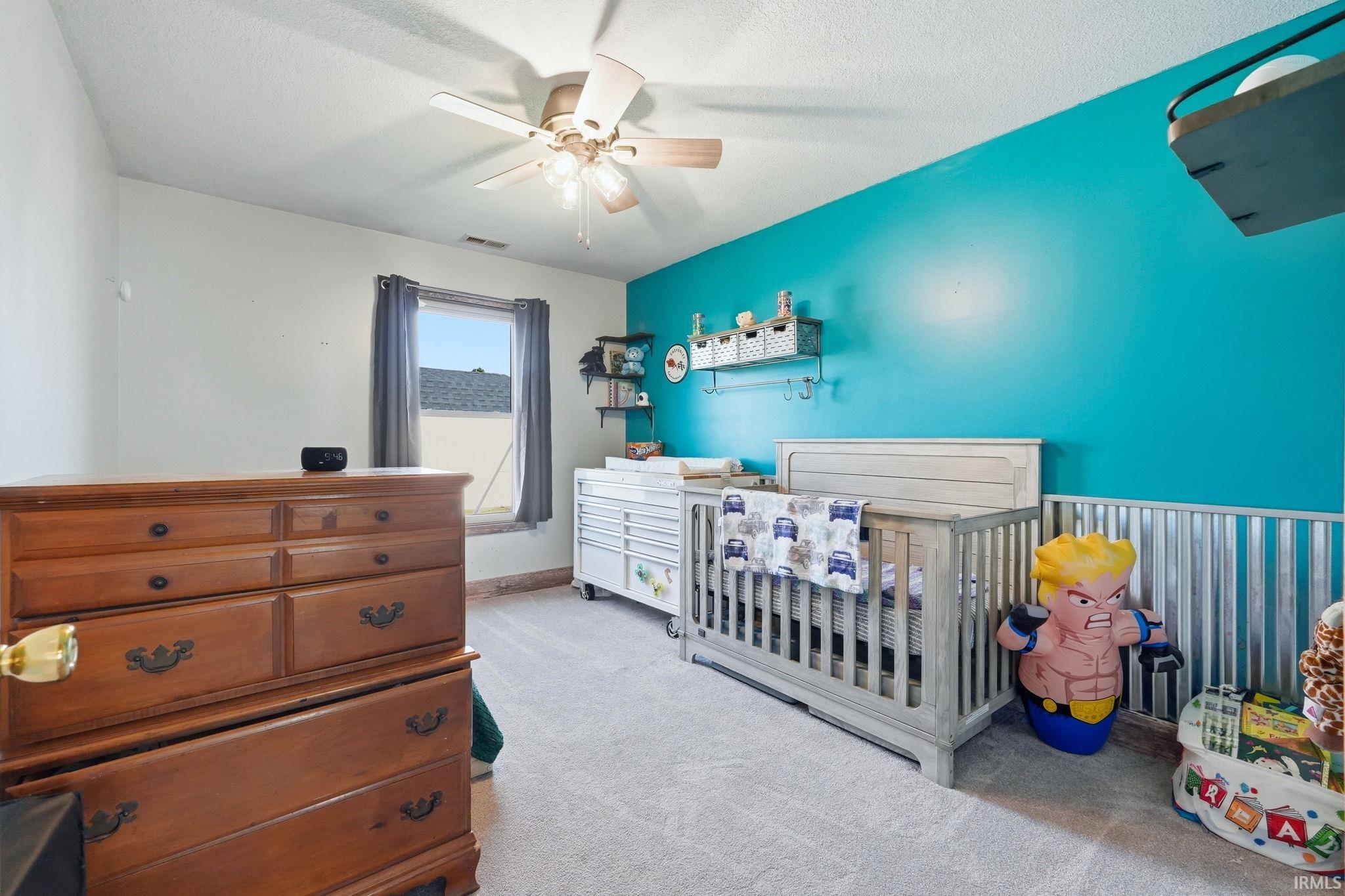 Room featuring a light grey carpet, a window with grey curtains, and a ceiling fan with integrated lighting