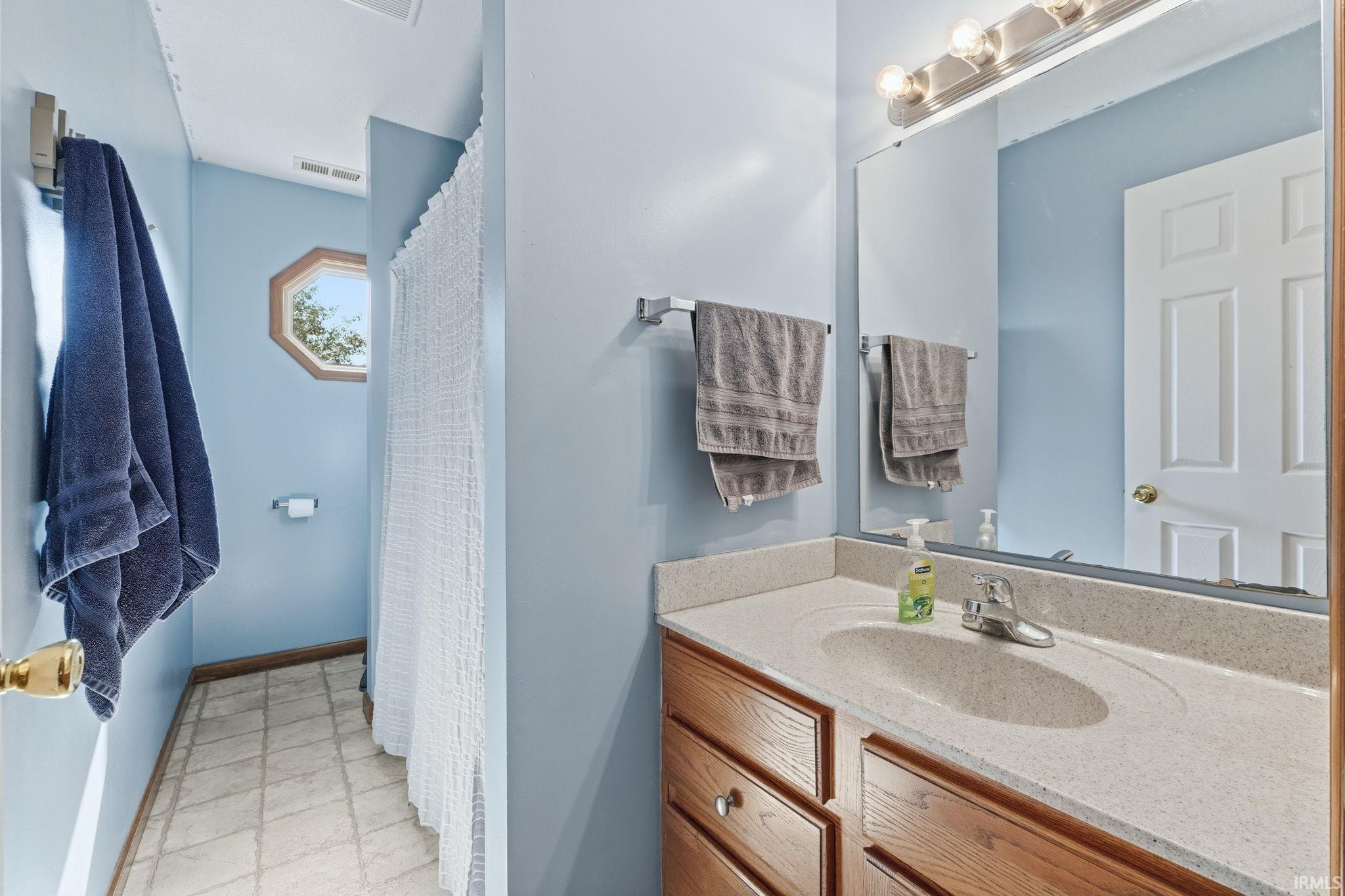 Bathroom featuring a single vanity with a stone-finish countertop and an integrated sink