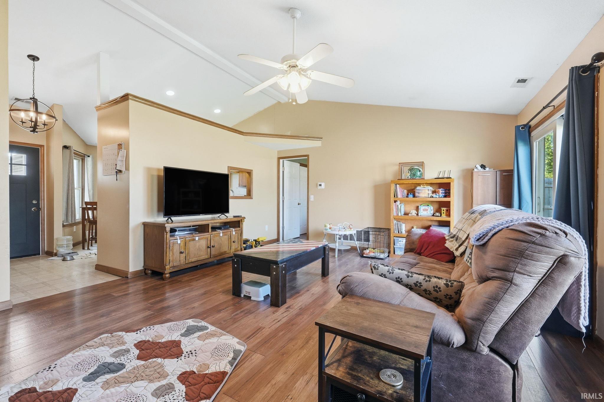 Living area featuring wood-finish flooring, vaulted ceiling with a ceiling fan, recessed lighting, and a sliding glass door