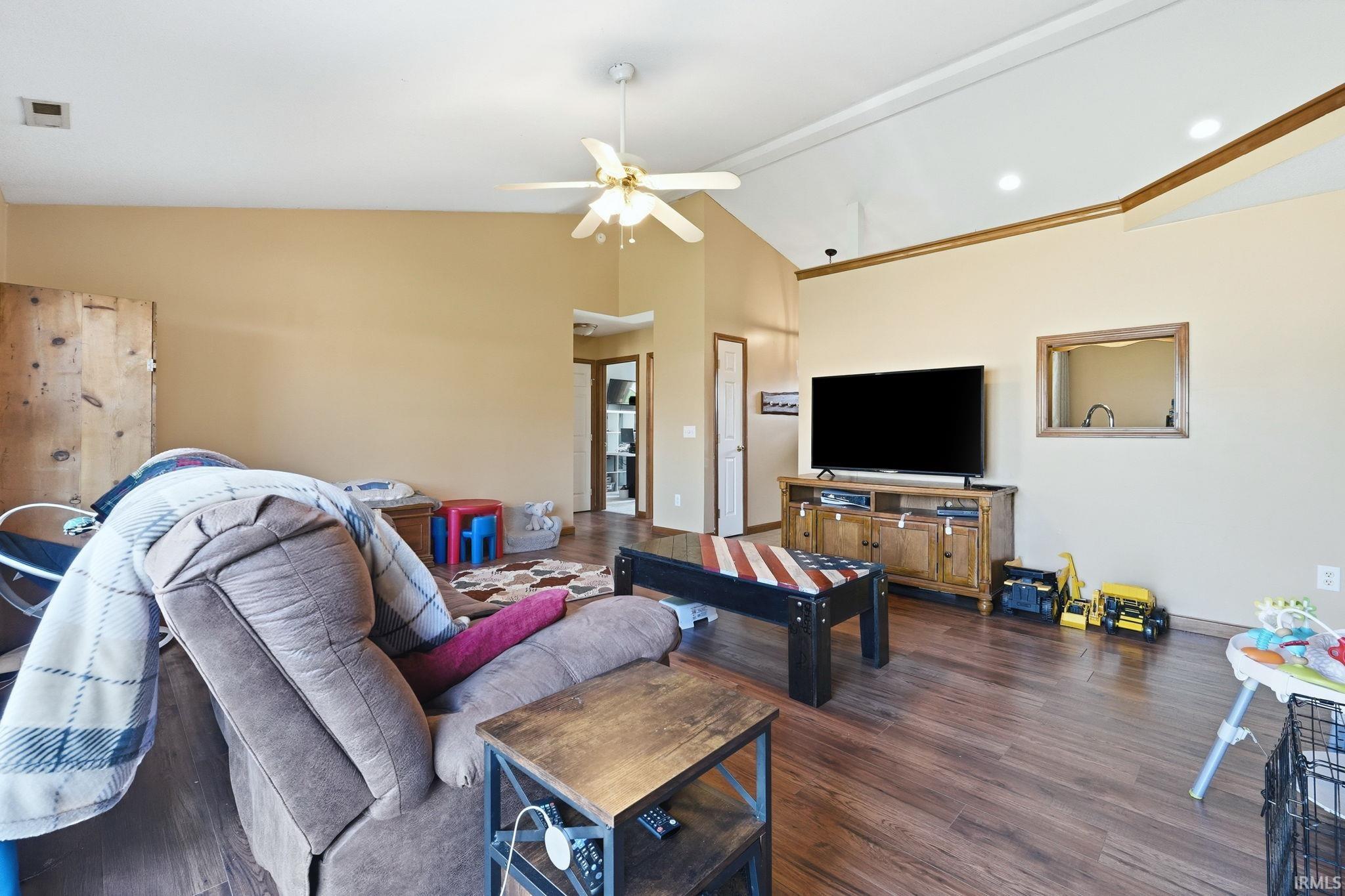 Spacious living area featuring vaulted ceilings, ceiling fan, recessed lighting, wood-finish flooring, and a built-in media console