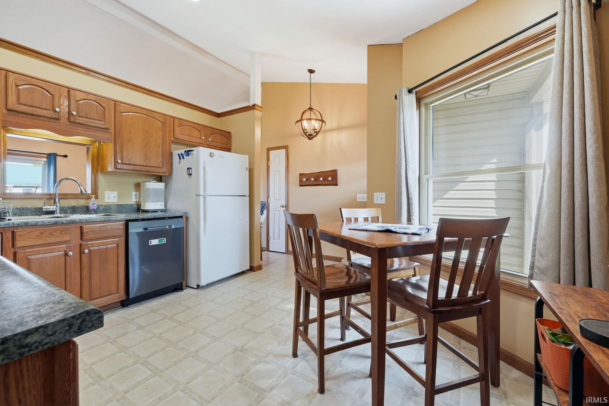 Kitchen area featuring wood-finish cabinetry, dark countertop, and integrated dishwasher