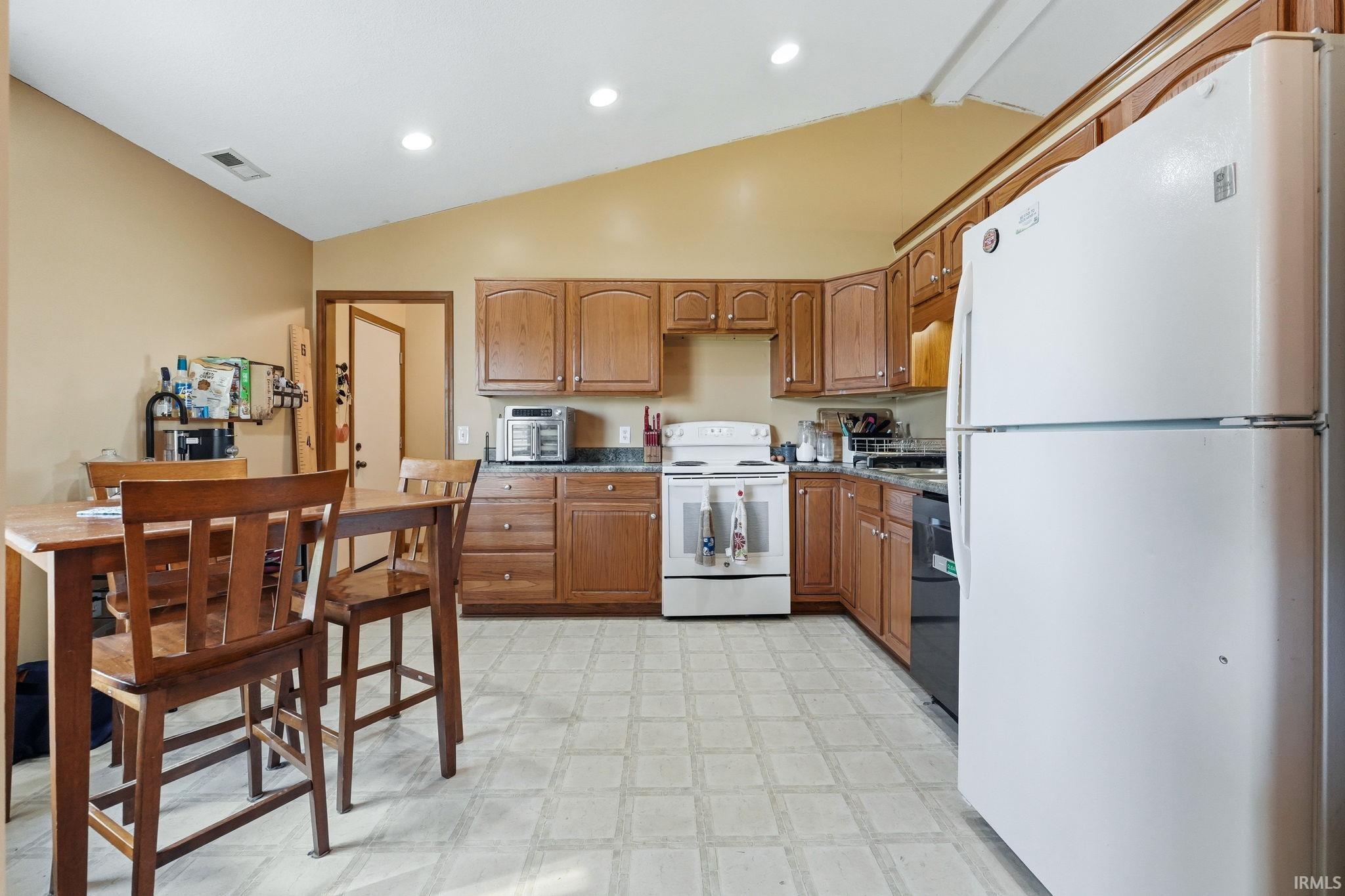 Kitchen featuring wood-finish cabinetry, solid surface countertops, and a white refrigerator