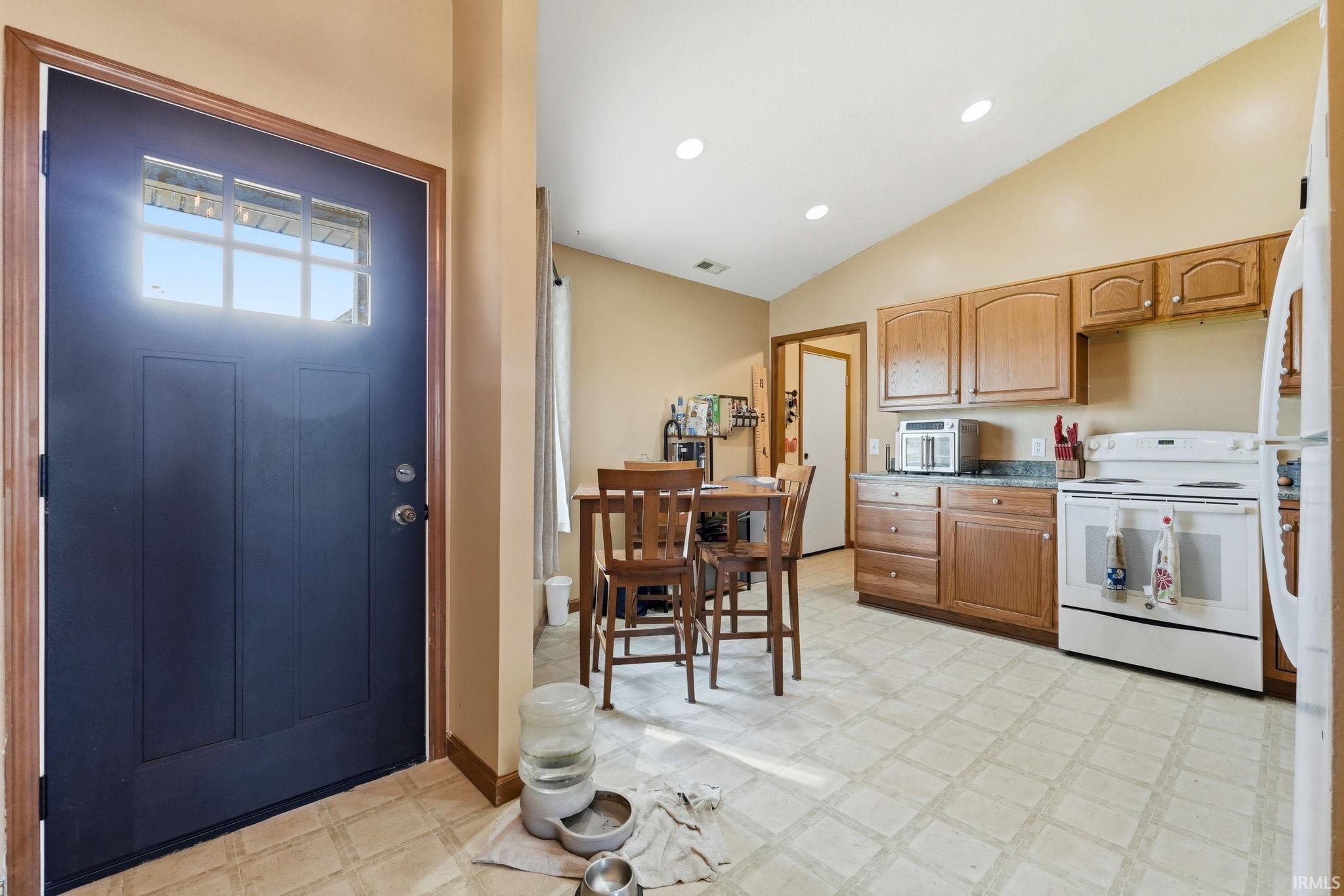 Entryway with a dark paneled door featuring an upper window panel, opening into a kitchen area