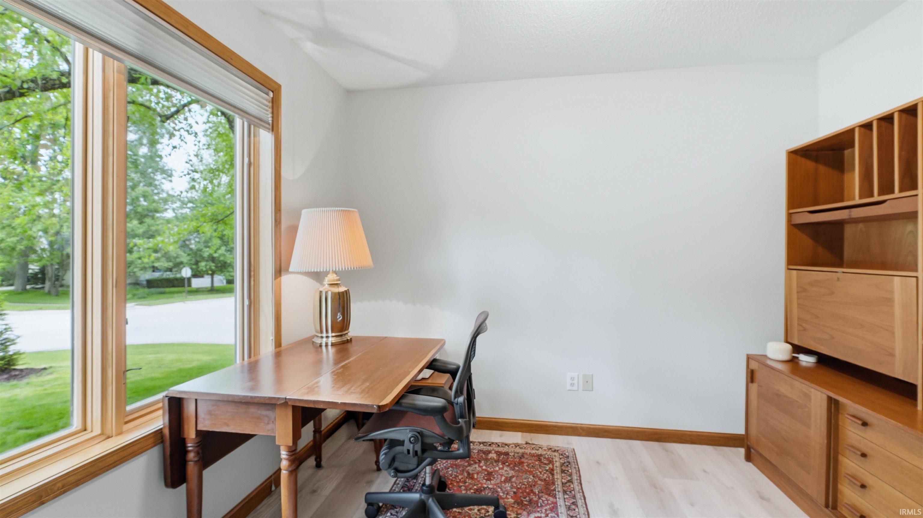 Bright interior space featuring a large window with wood trim, light wood-finish flooring, and white painted walls