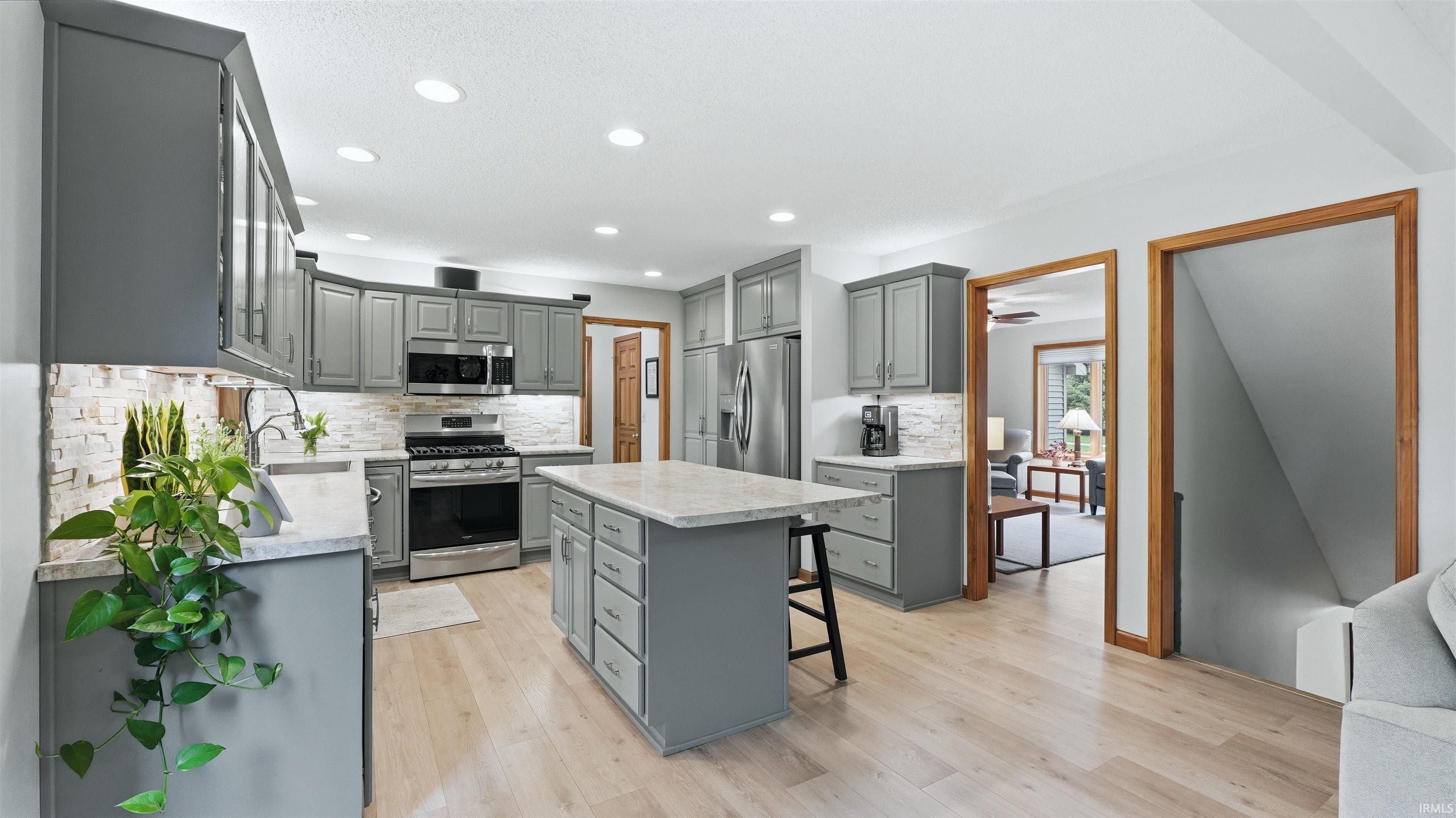 Kitchen featuring light gray cabinetry with brushed nickel hardware, stainless steel appliances, and light wood-finish flooring