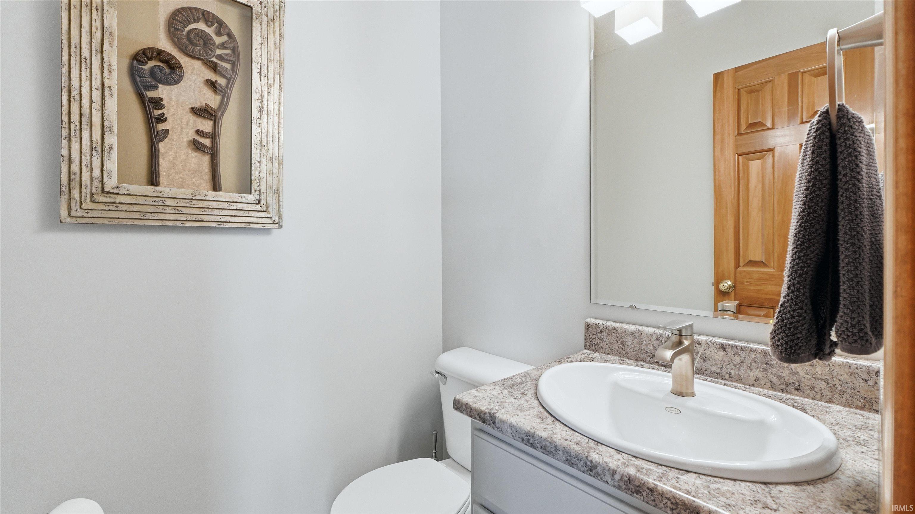 Vanity with an oval undermount sink, speckled countertop, and brushed nickel single-handle faucet