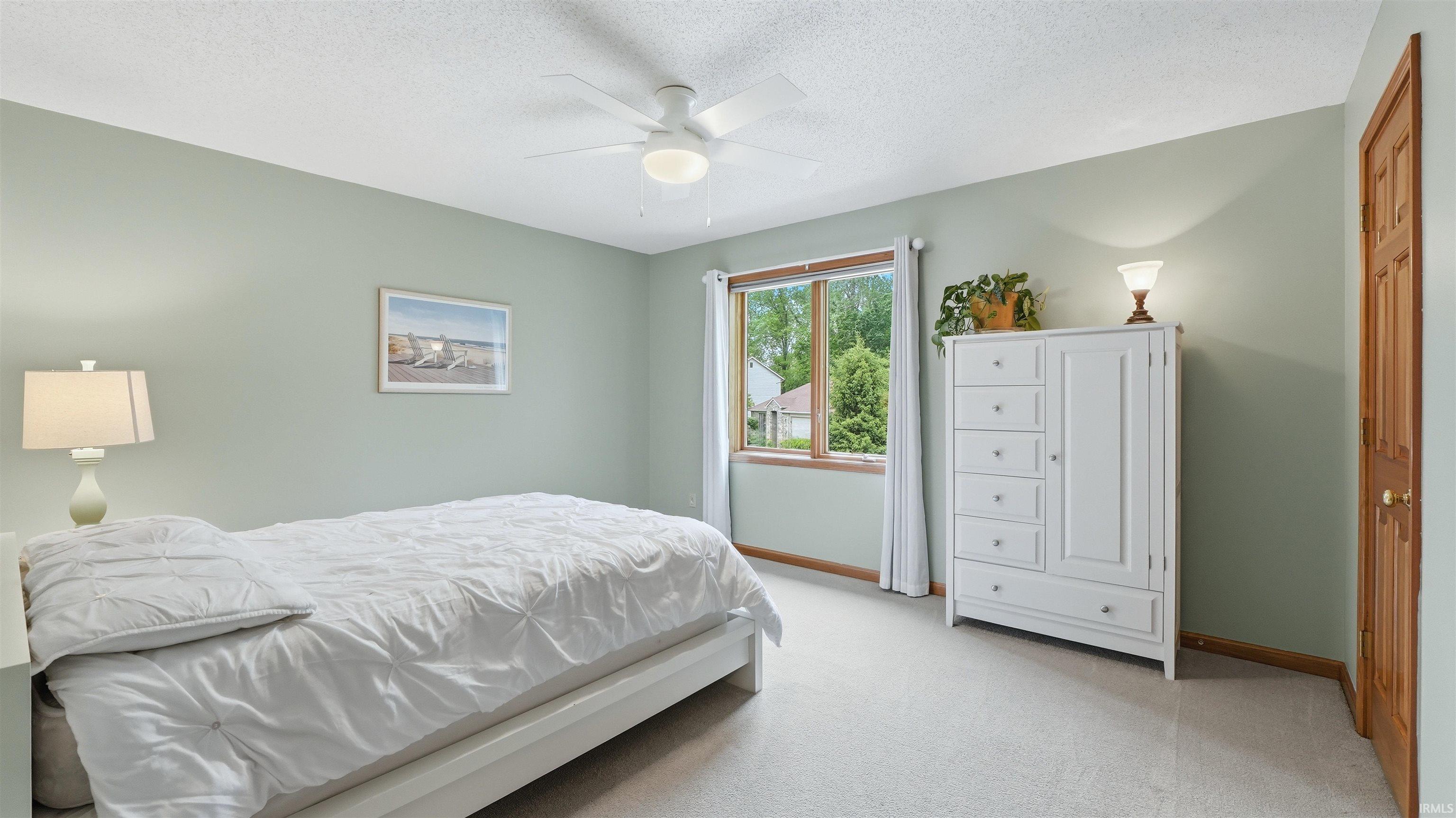Bedroom featuring light green walls and light-colored carpet