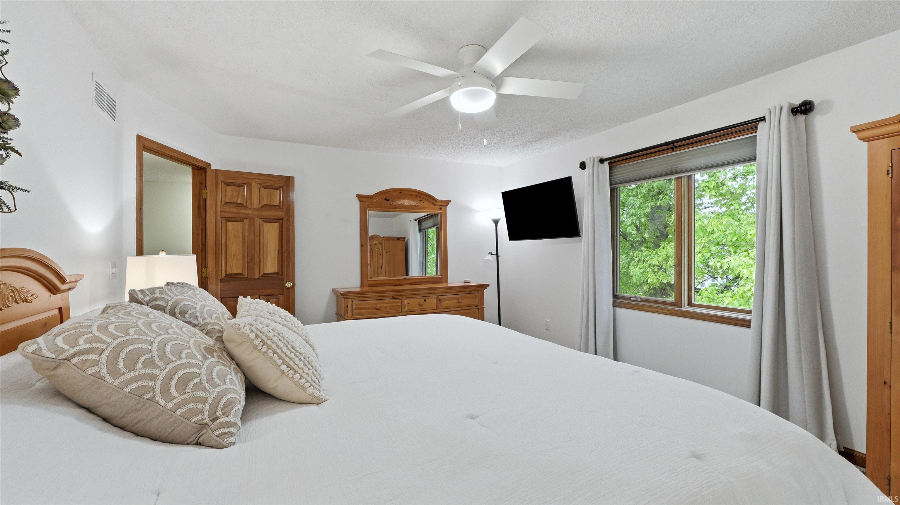 Bright interior space featuring a window with green foliage visible, a ceiling fan, and wood-paneled doors