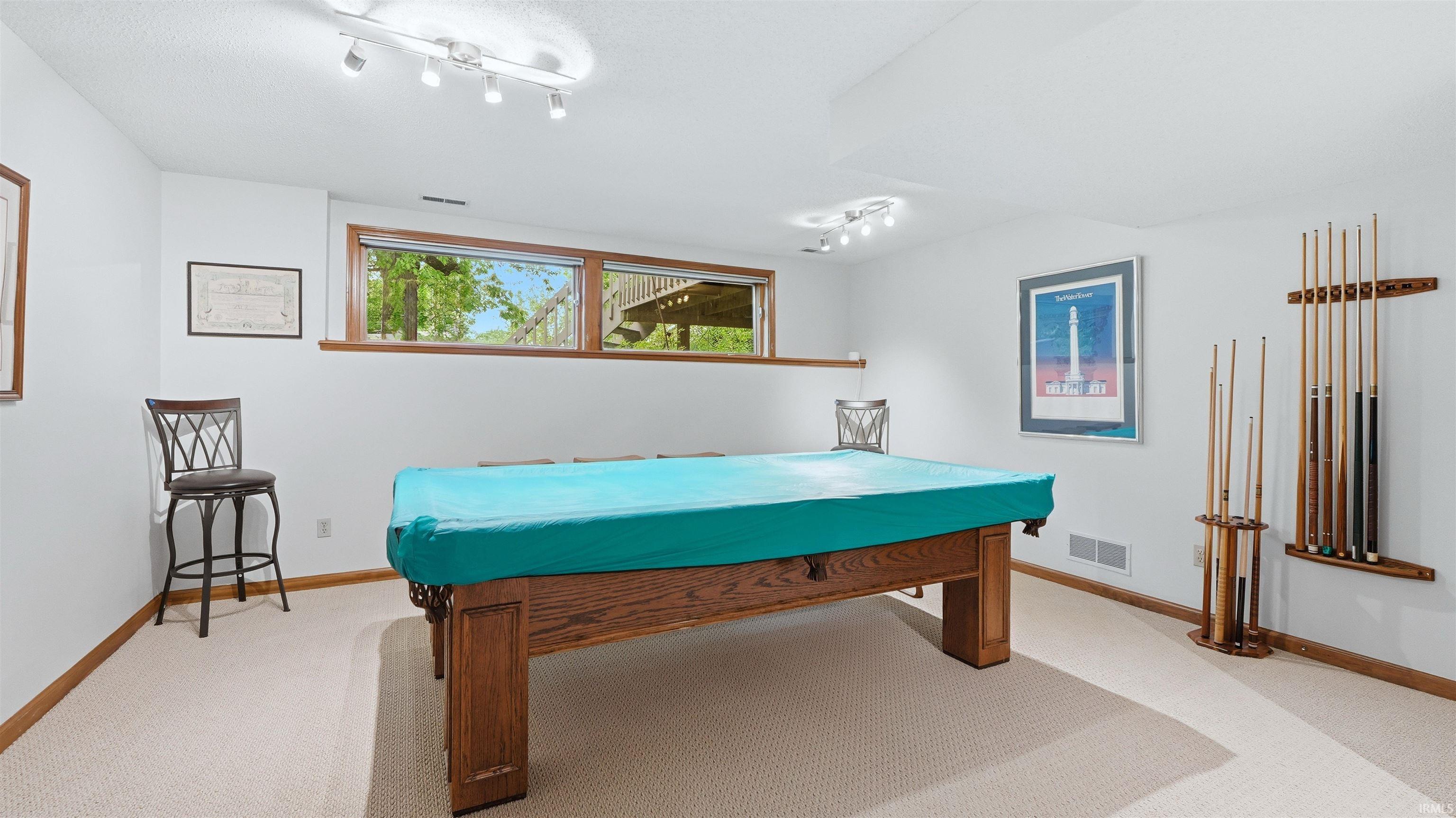 Recreation room featuring track lighting, wood-trim windows, and neutral carpet flooring