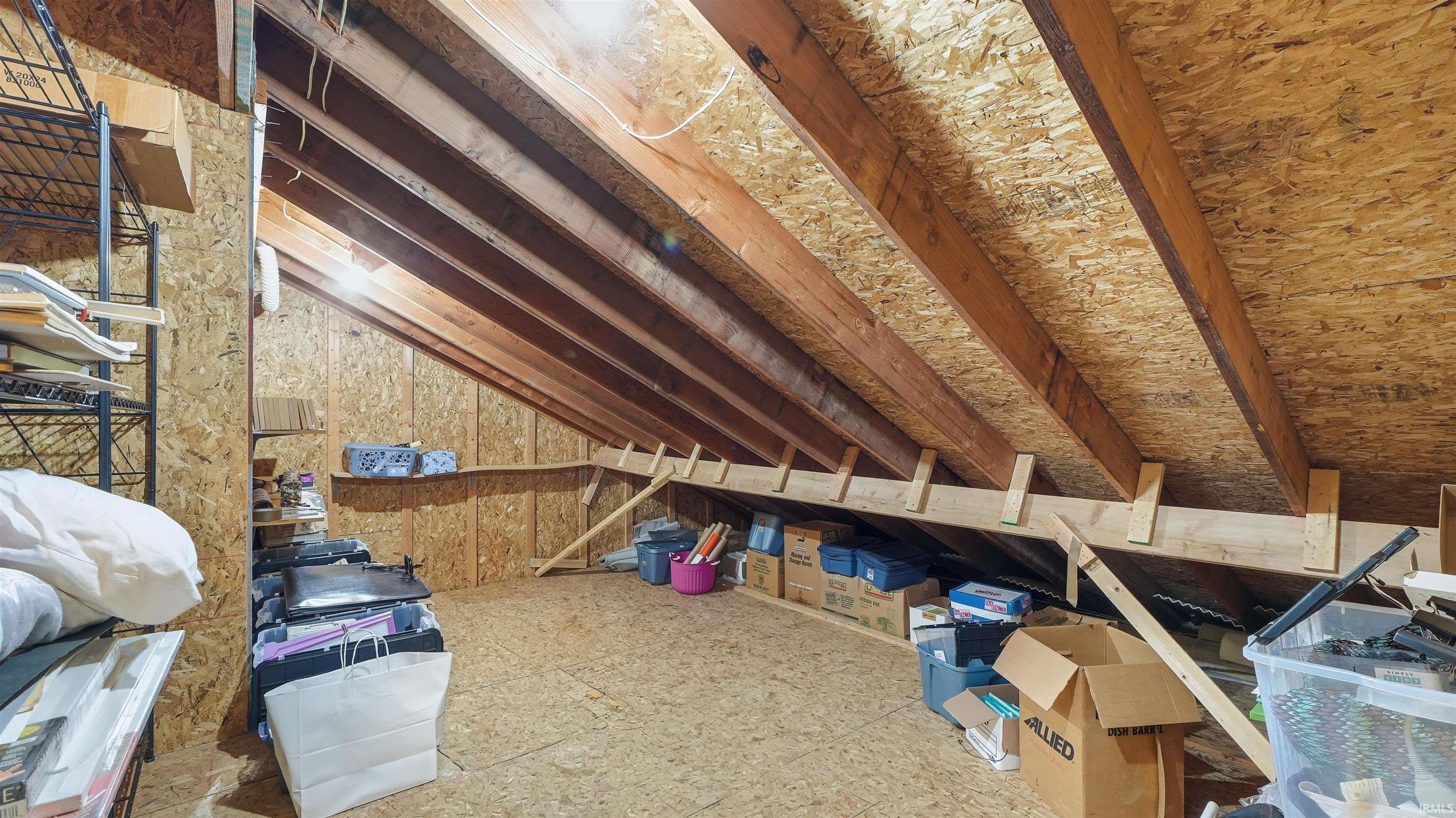 Spacious attic space featuring exposed wood rafters and oriented strand board walls and flooring