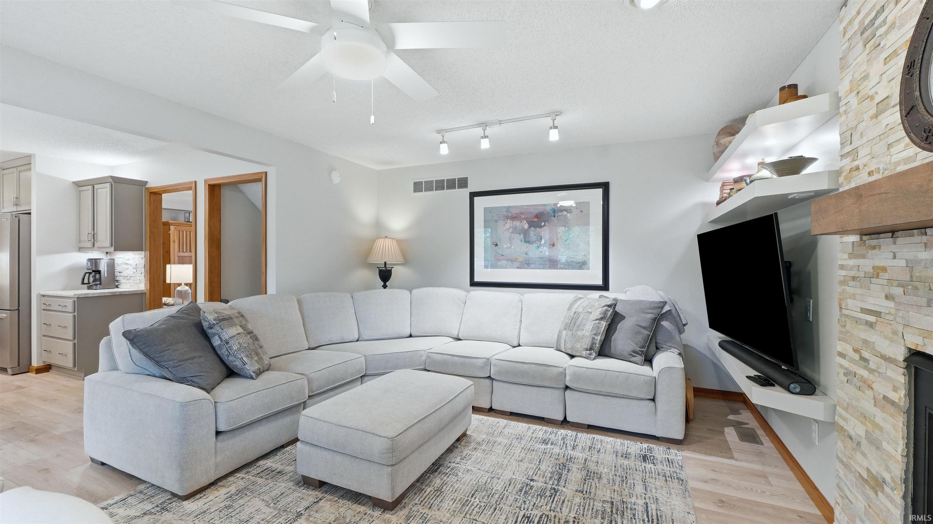 Living area featuring a stone-clad fireplace with wood mantel, built-in shelving, and wood-finish flooring