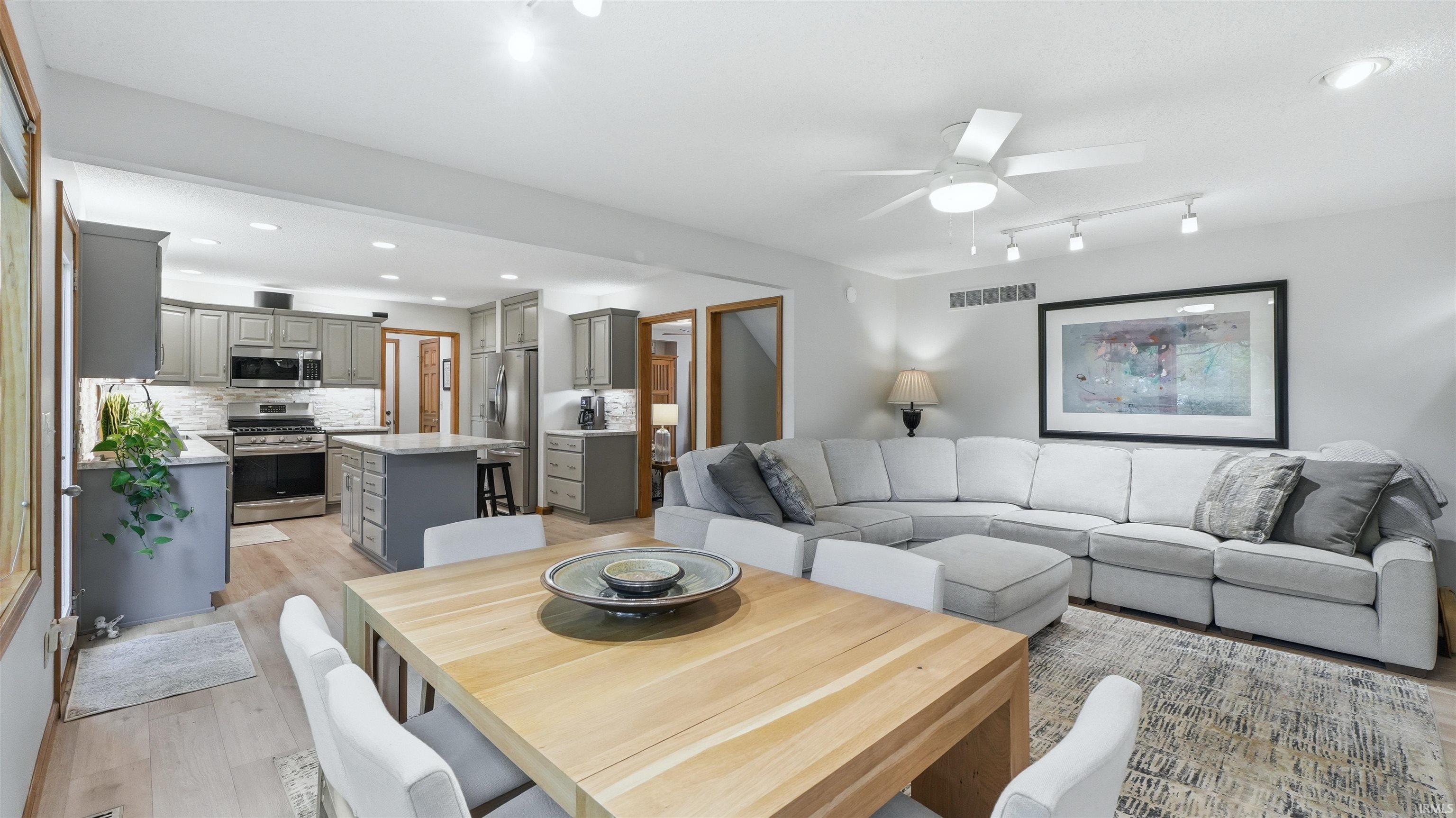 Open-concept living area featuring a kitchen with gray cabinetry, stainless steel appliances, and a central island