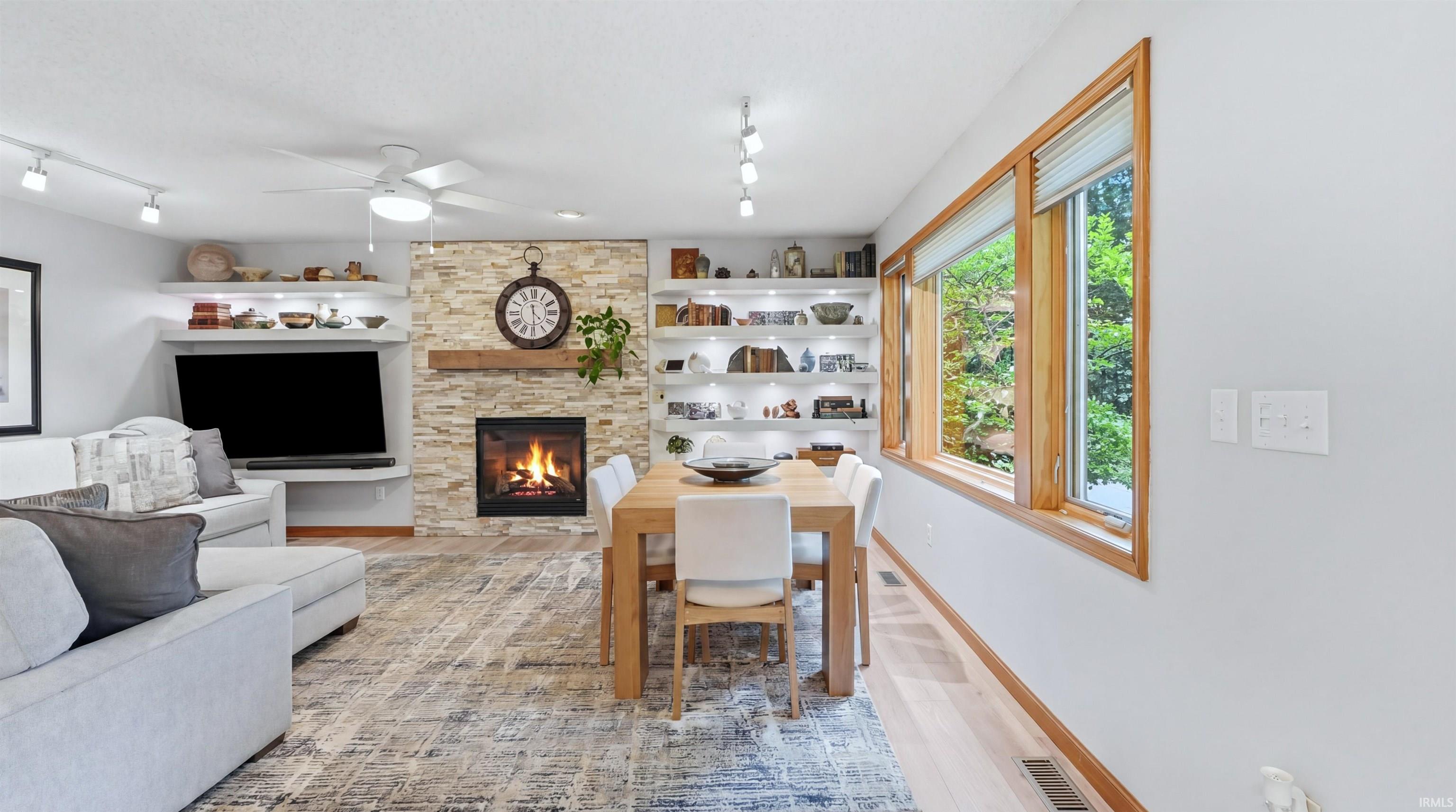 Open-concept living and dining area featuring a stone-clad fireplace with a wood mantel