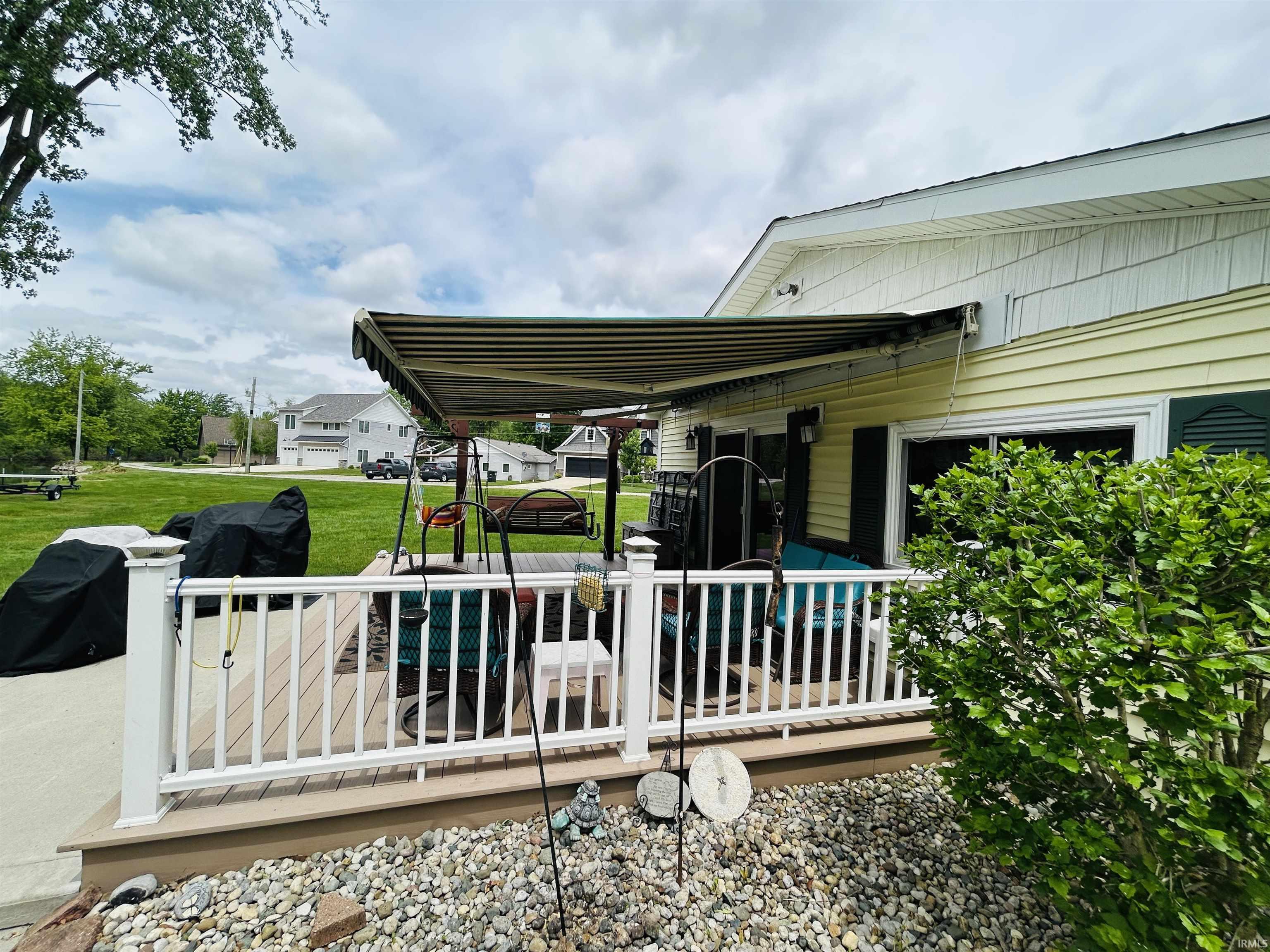 Expansive deck featuring white railing and an overhead retractable awning