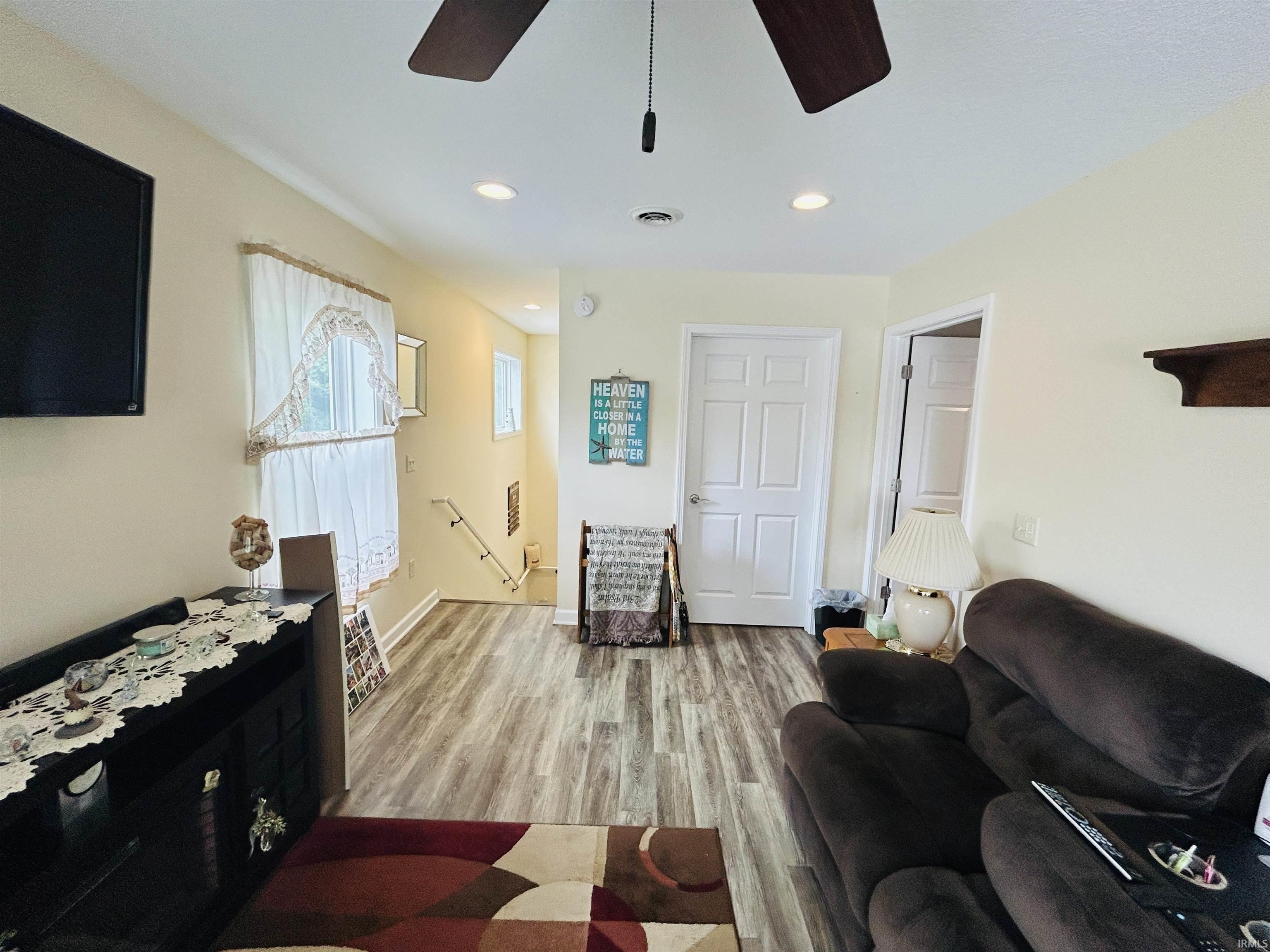 Open-concept living area featuring wood-finish flooring, recessed lighting, a ceiling fan, and white paneled doors