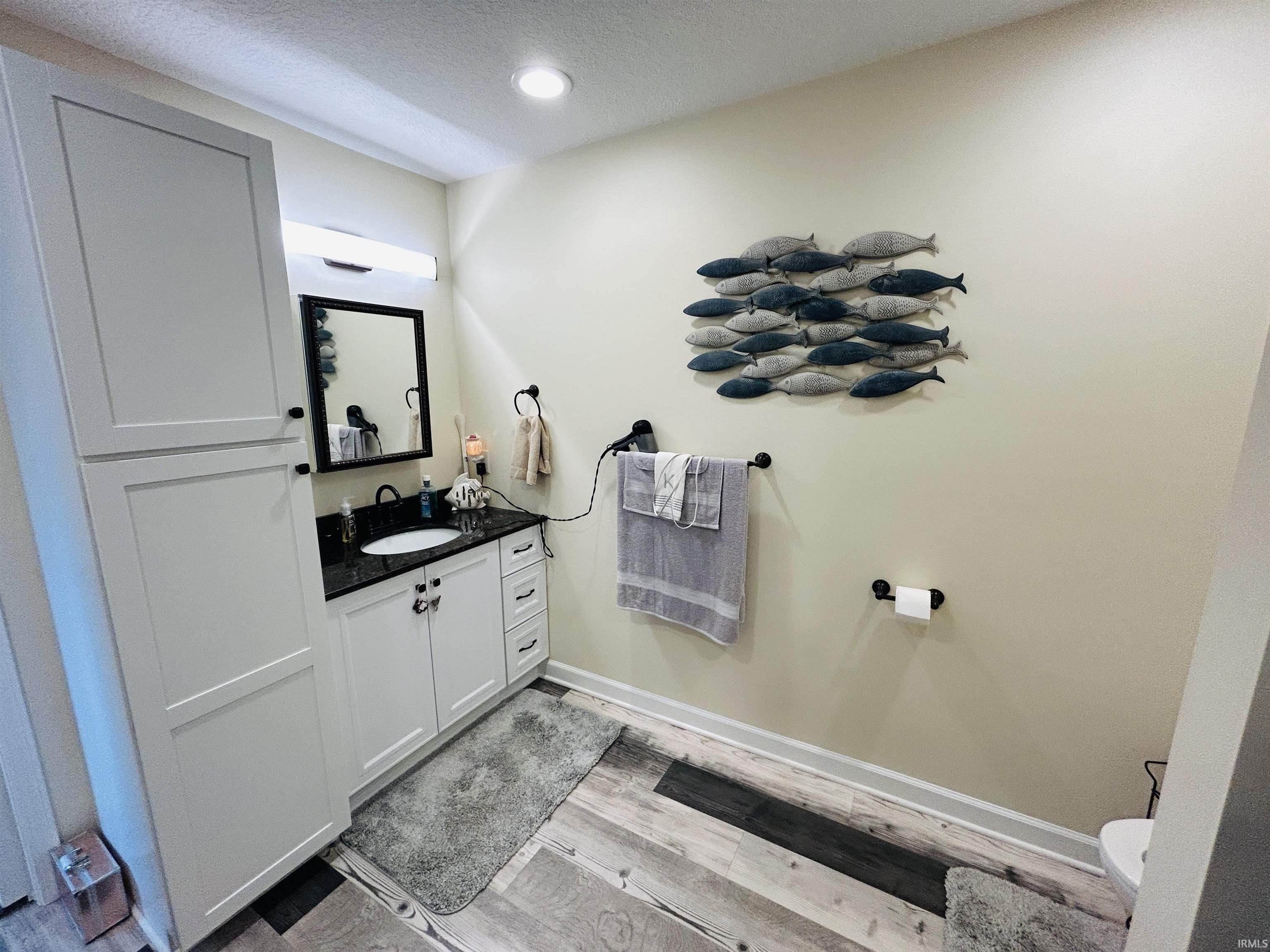 Bathroom vanity with white shaker-style cabinetry, a dark countertop, and a white undermount sink