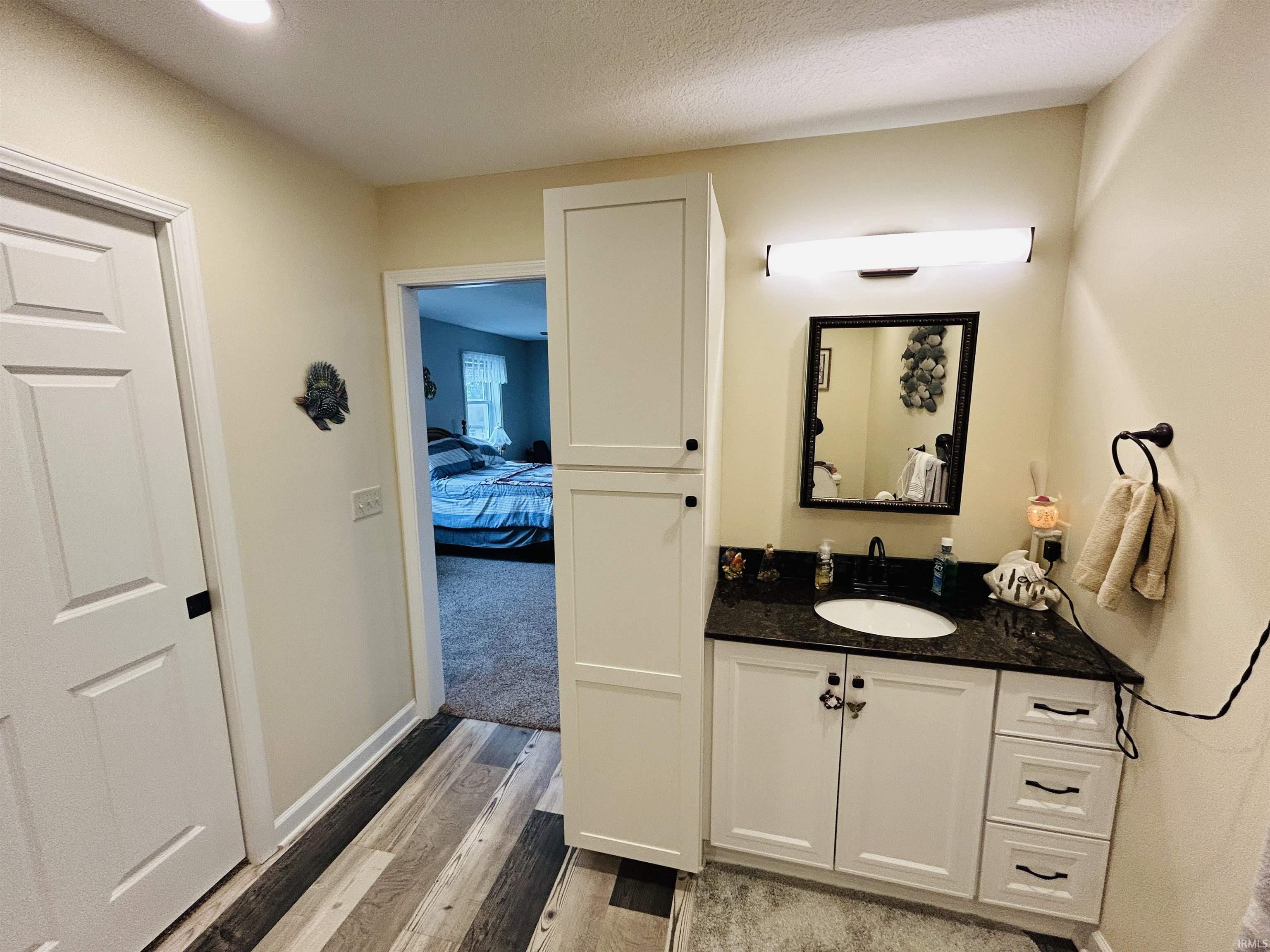 Bathroom vanity featuring a black countertop, undermount sink, and matte black hardware