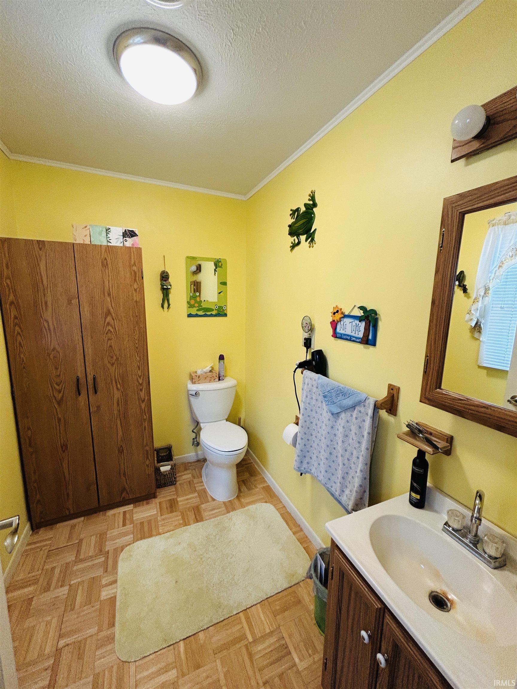 Bathroom featuring a wood-finish tile floor, a white toilet, and a vanity with a white countertop and double-handle faucet