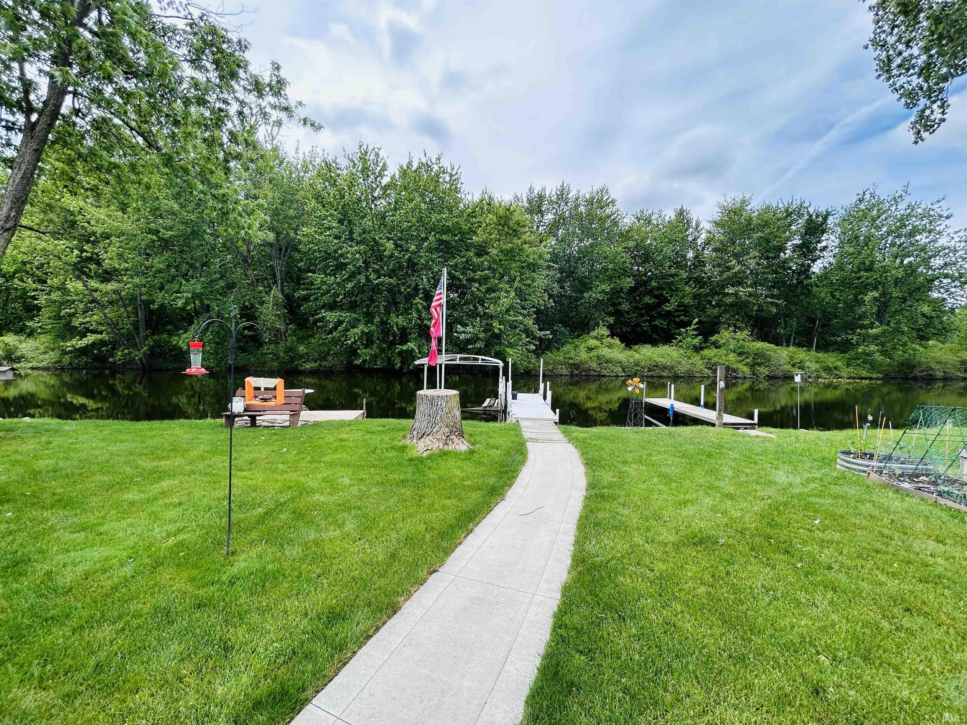 Expansive green lawn with a paved pathway leading to a waterfront area