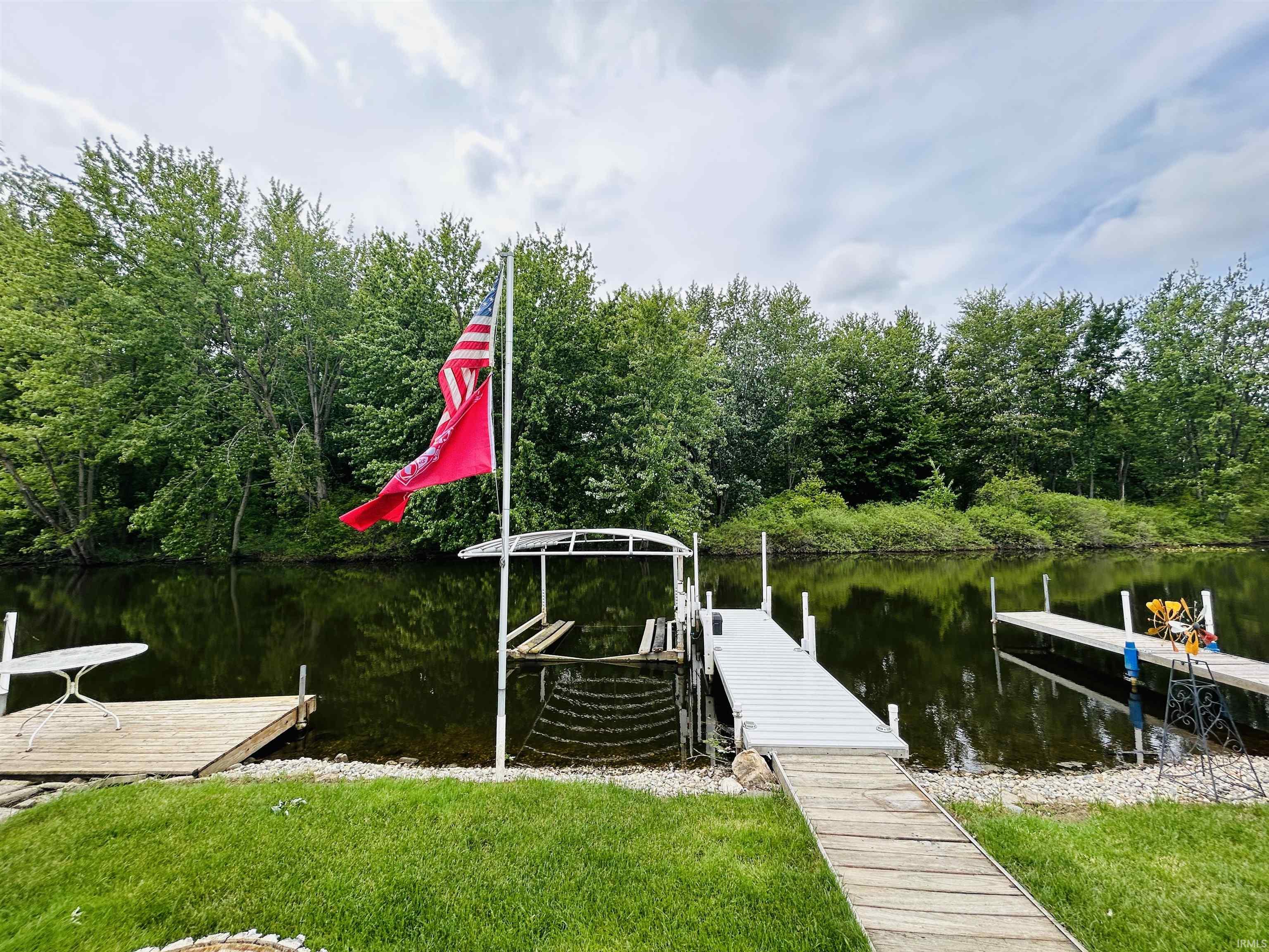 Waterfront property featuring multiple docks, a boat lift, and lush green landscaping