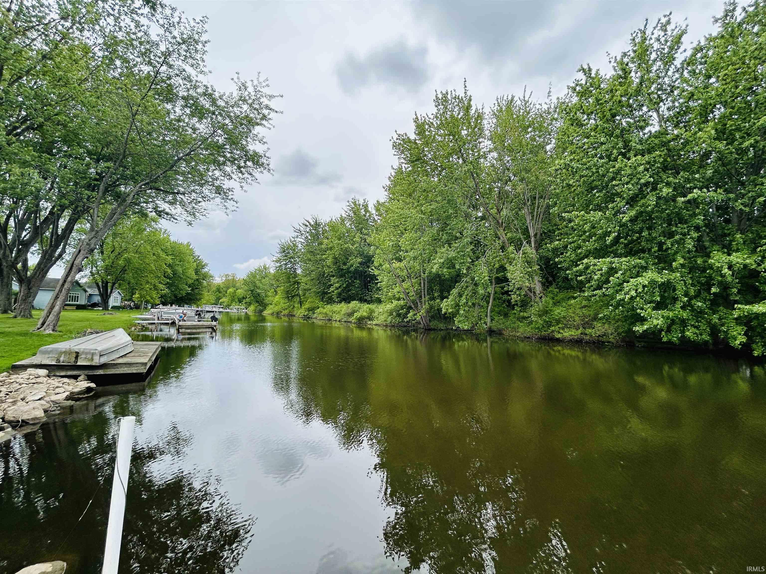 Waterfront property featuring a private dock, lush green trees, and natural shoreline