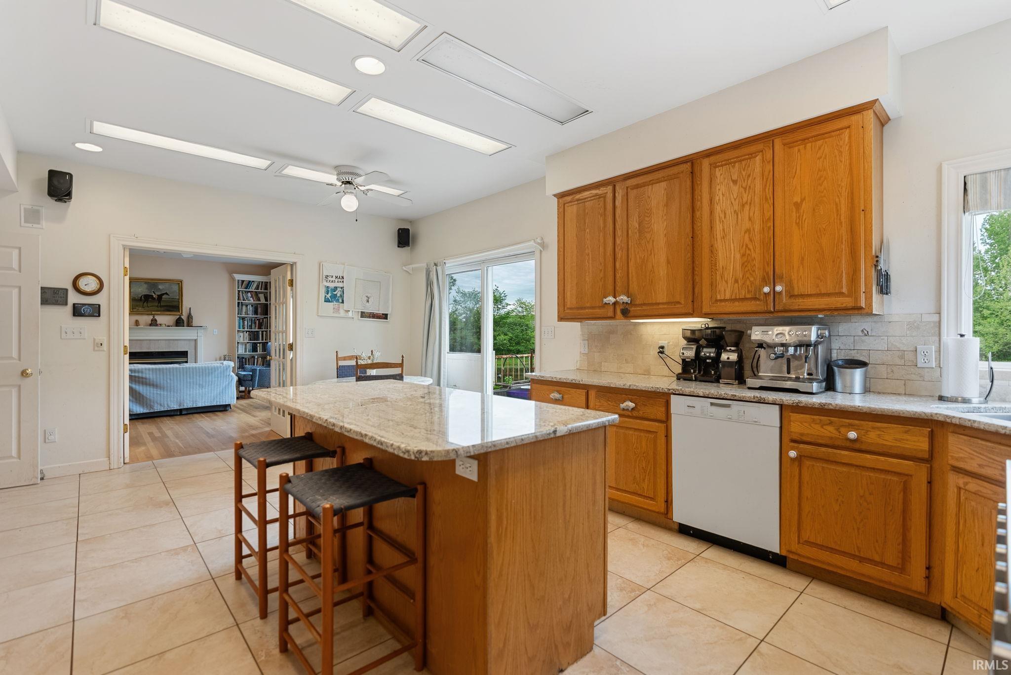 Kitchen featuring stone-finish flooring, wood cabinetry, stone countertops, and a full suite of appliances