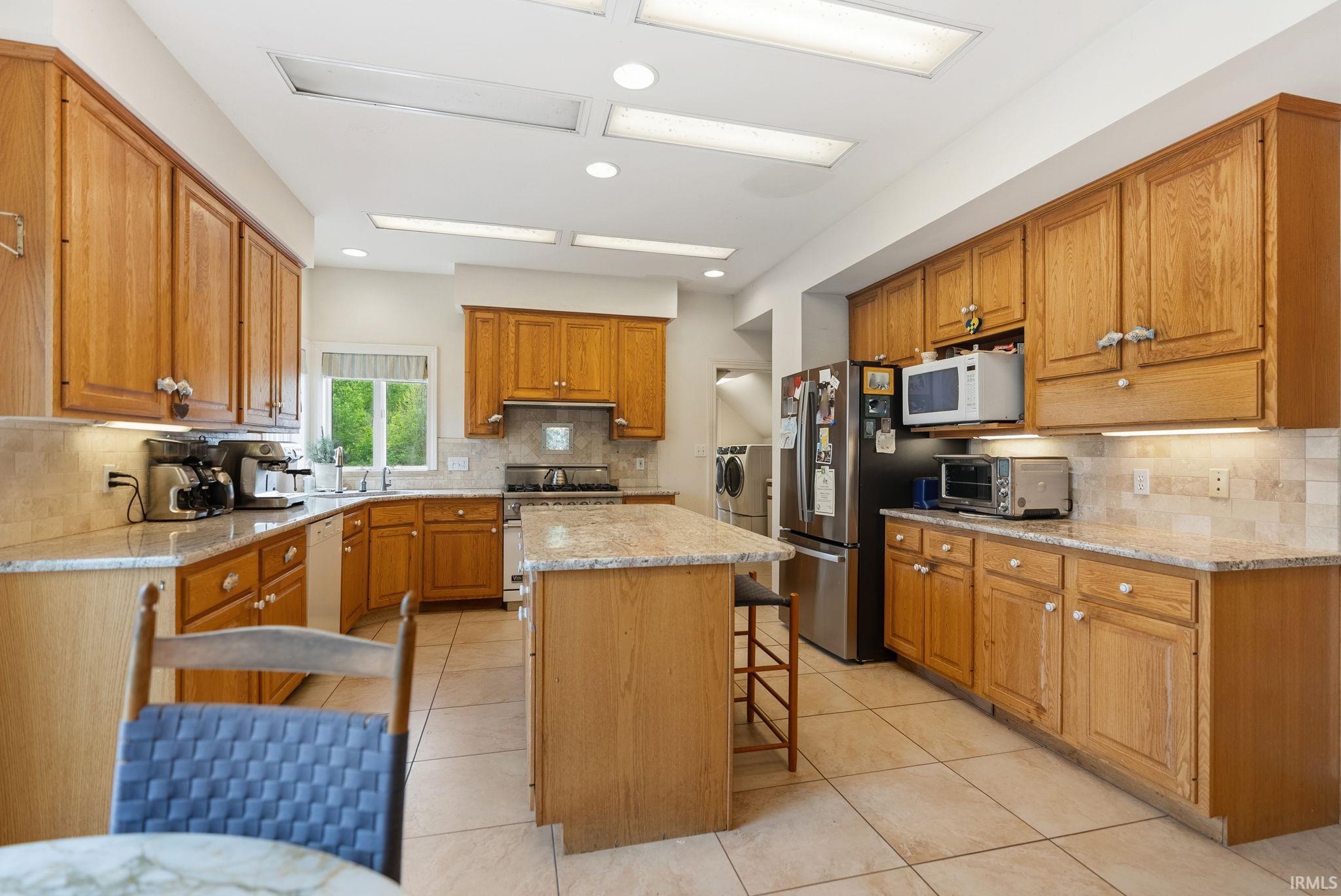 Kitchen featuring wood cabinetry, light-toned stone countertops, and tile flooring
