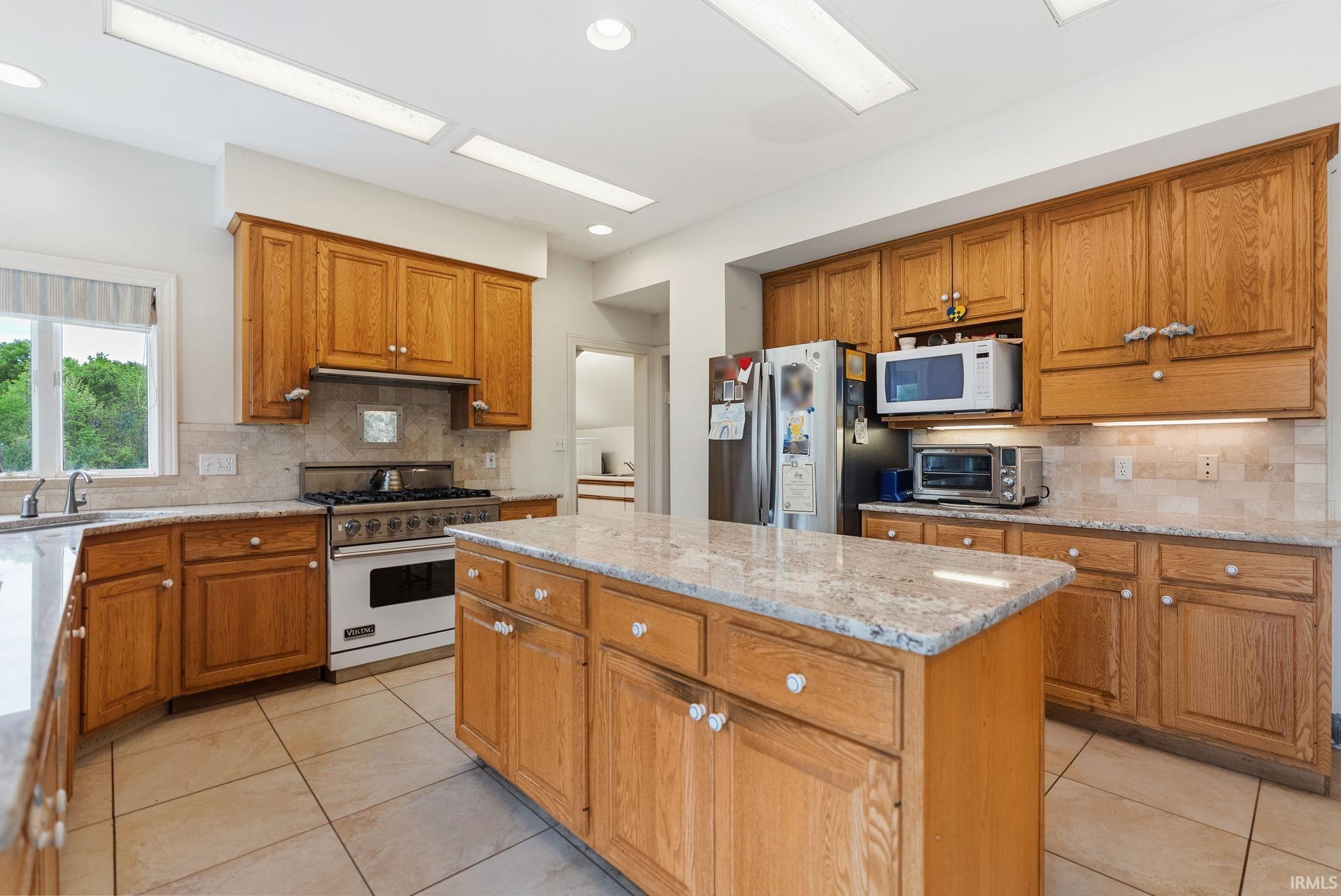 Kitchen featuring a central island with a granite countertop, wood cabinetry, and tile flooring
