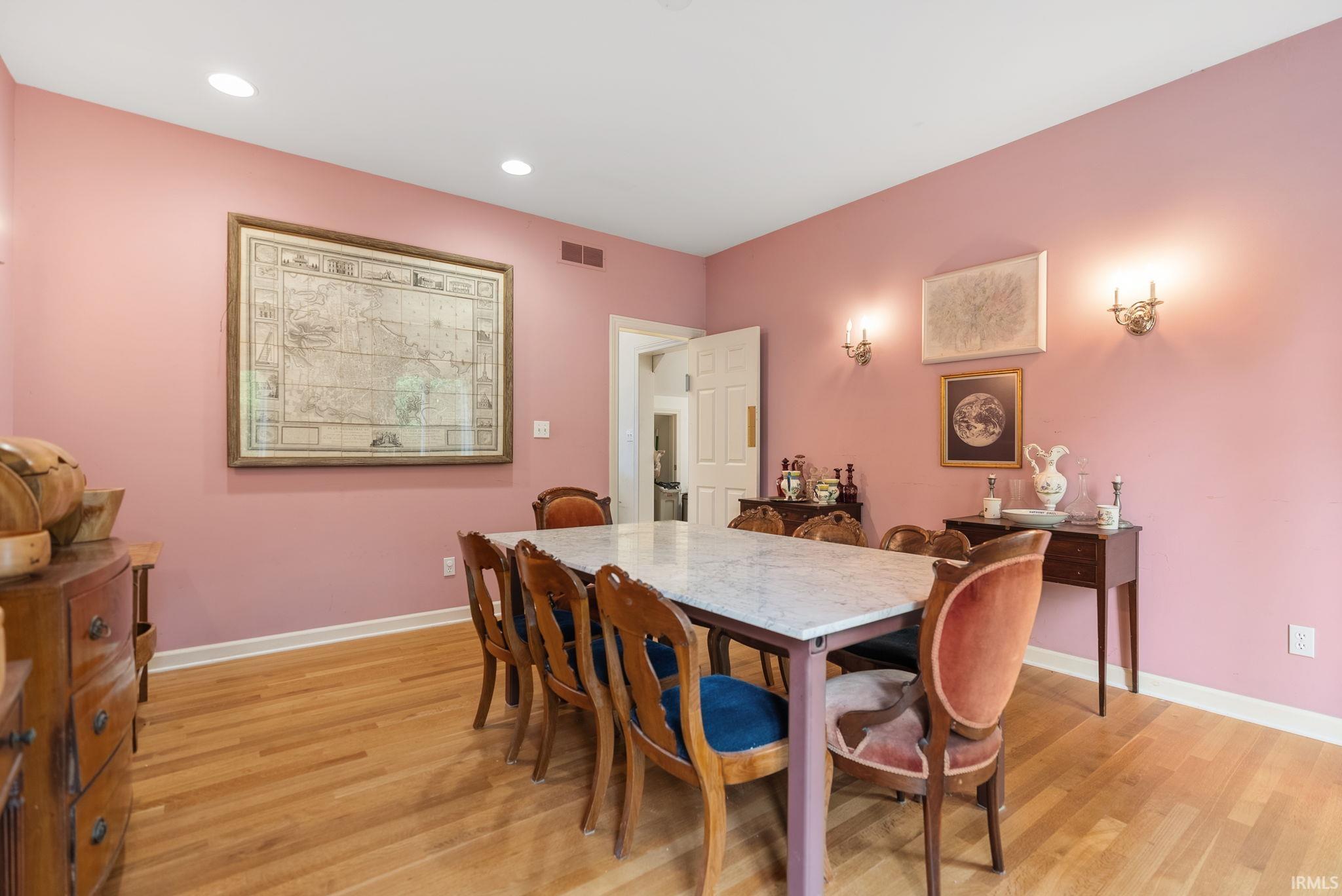 Spacious room featuring wood-finish flooring, recessed ceiling lighting, and wall sconces