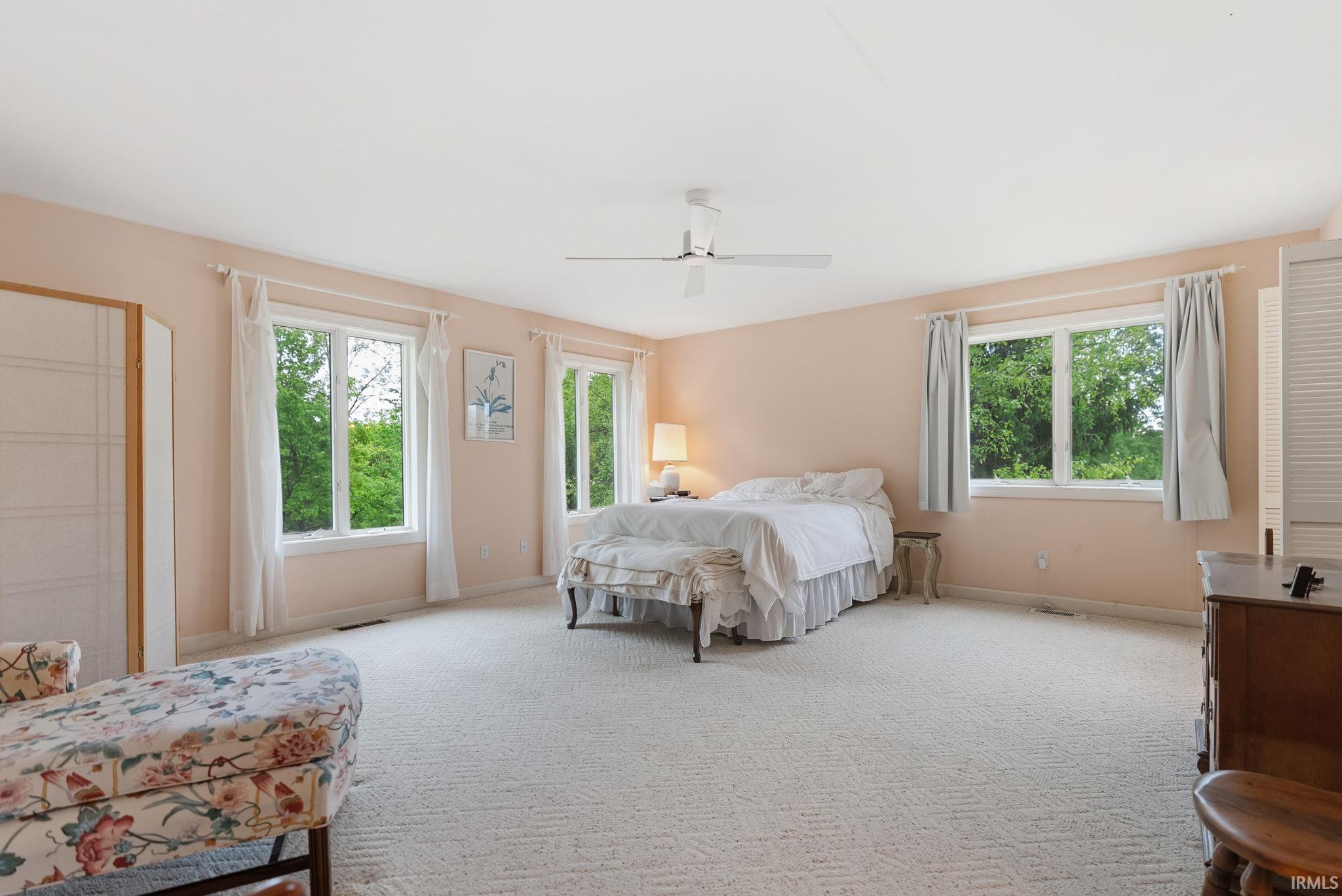 Expansive bedroom featuring wall-to-wall carpeting and four large windows