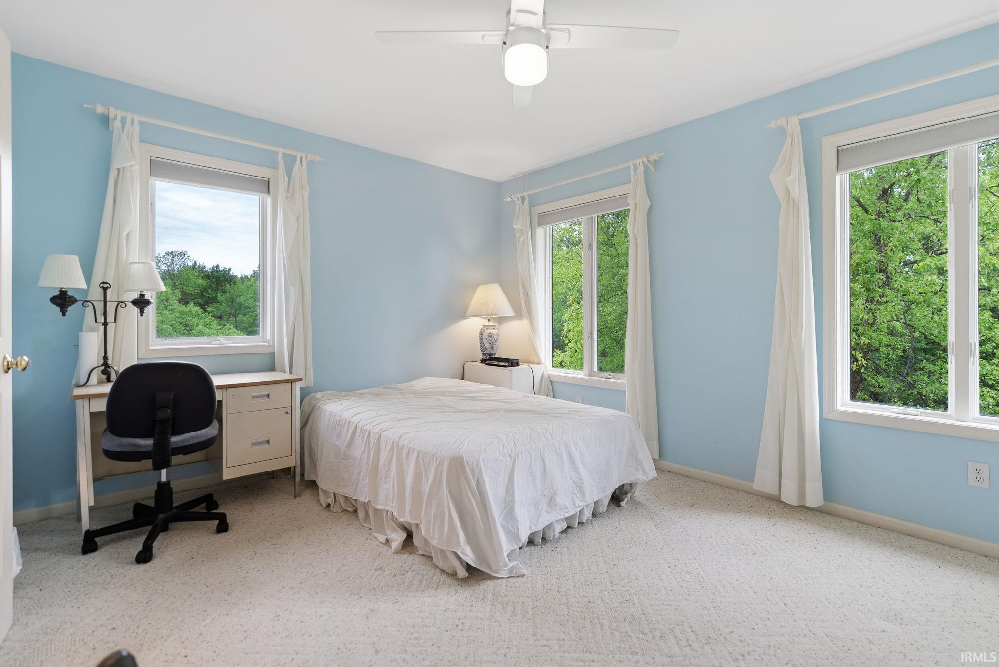 Bedroom featuring light blue walls and a white ceiling fan with integrated lighting