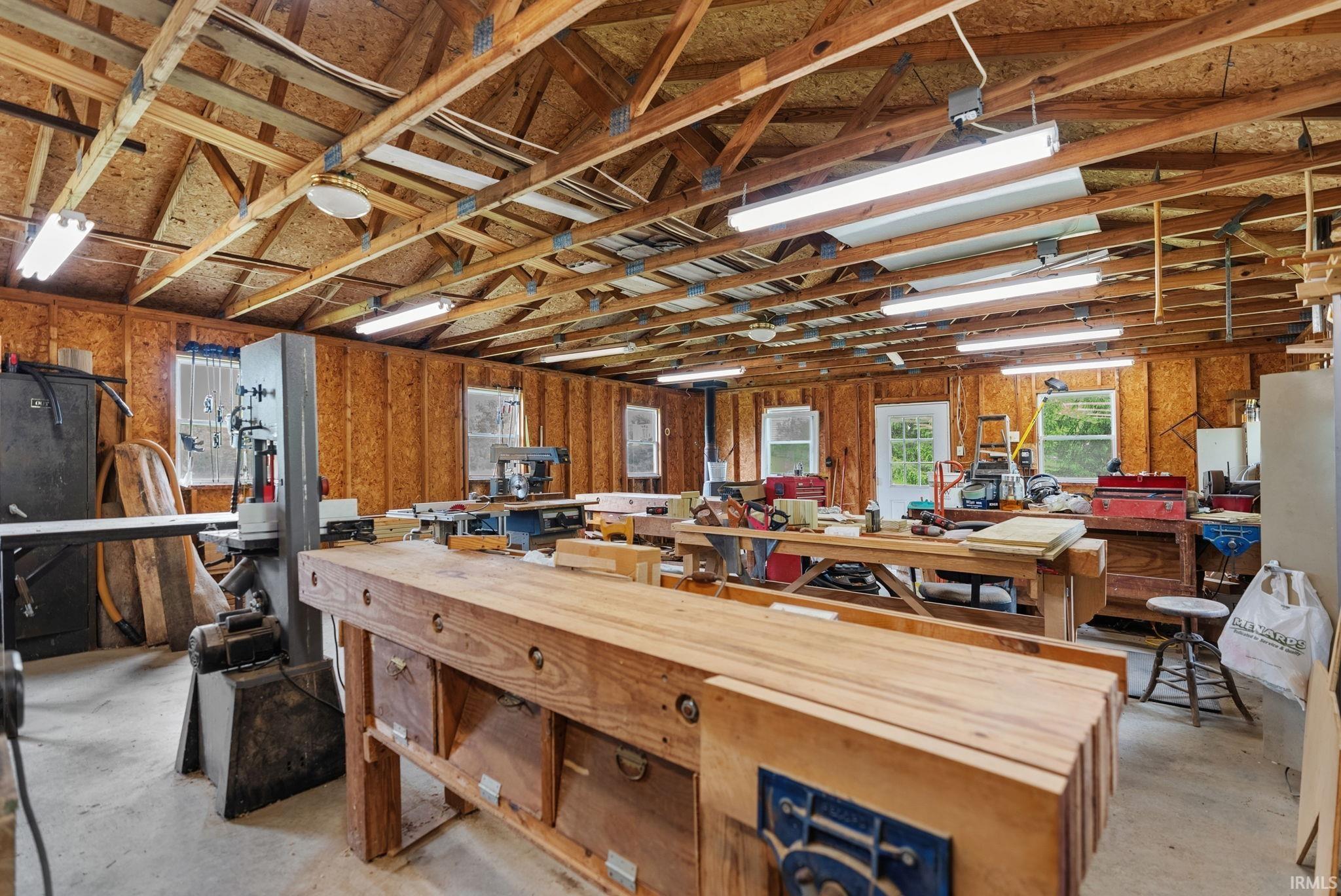 Spacious workshop featuring exposed wood beam ceilings and wood-finish wall paneling