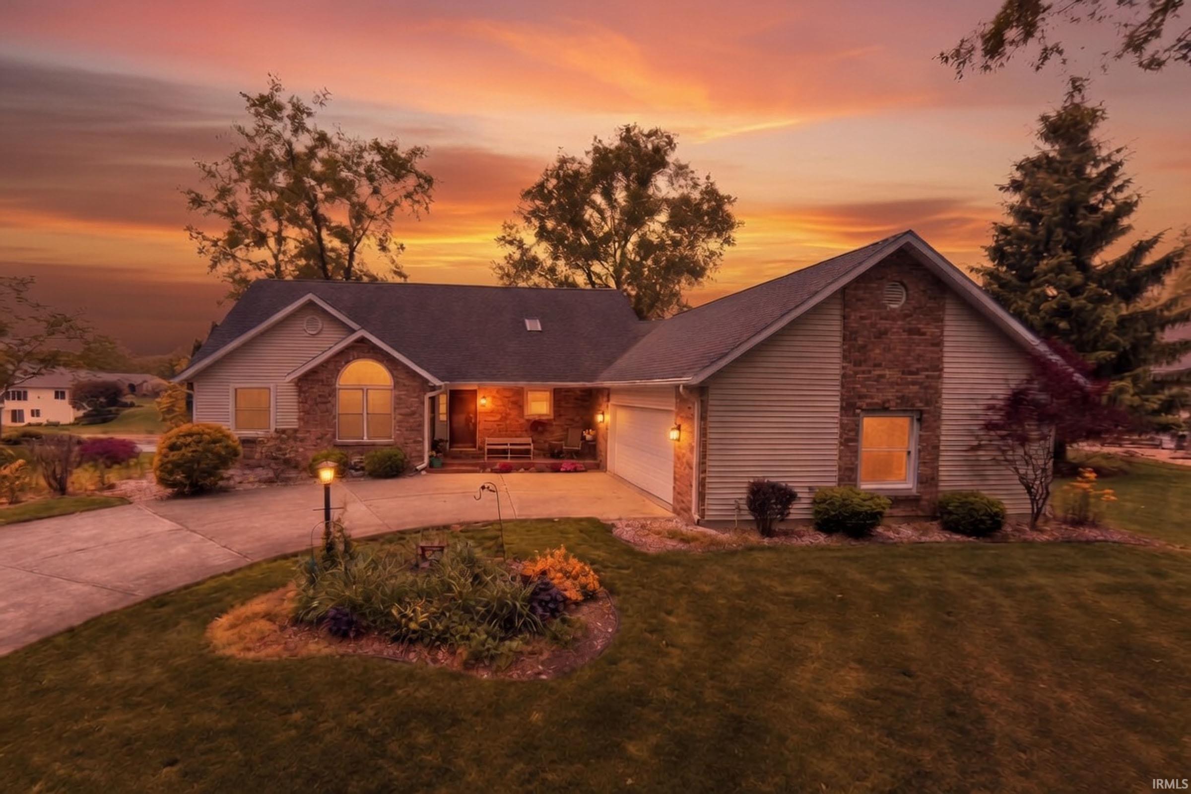 Ranch-style residence featuring a prominent stone and siding facade, an arched window accent, and an attached two-car garage