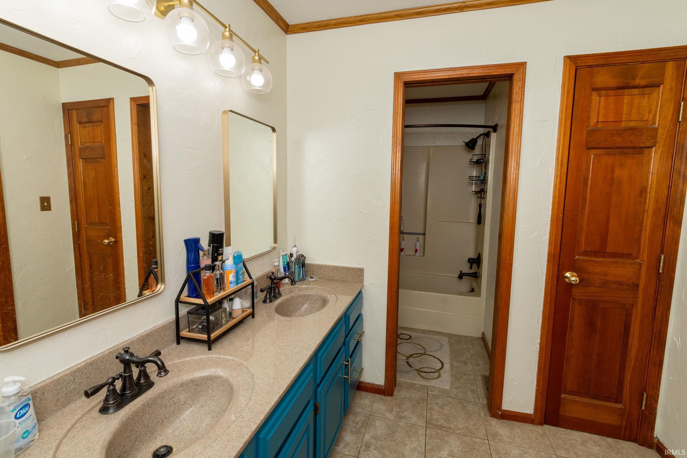 Bathroom featuring a dual vanity with integrated sinks, stone-finish countertop, and teal-painted cabinetry