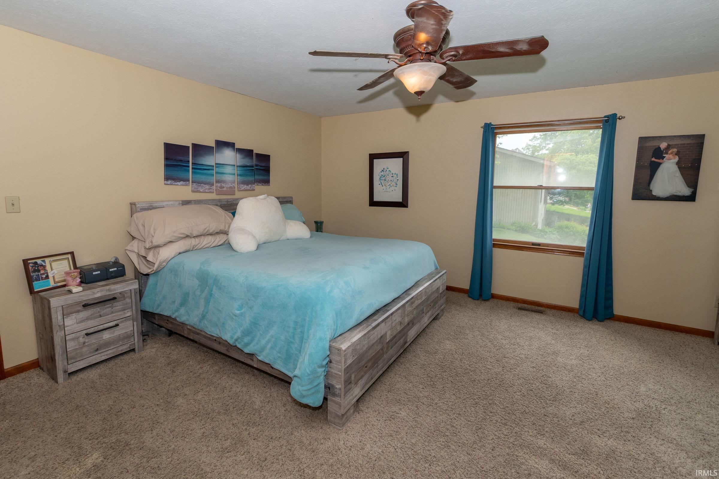 Carpeted room featuring a ceiling fan with integrated lighting, a window with a wood frame, and neutral-toned walls