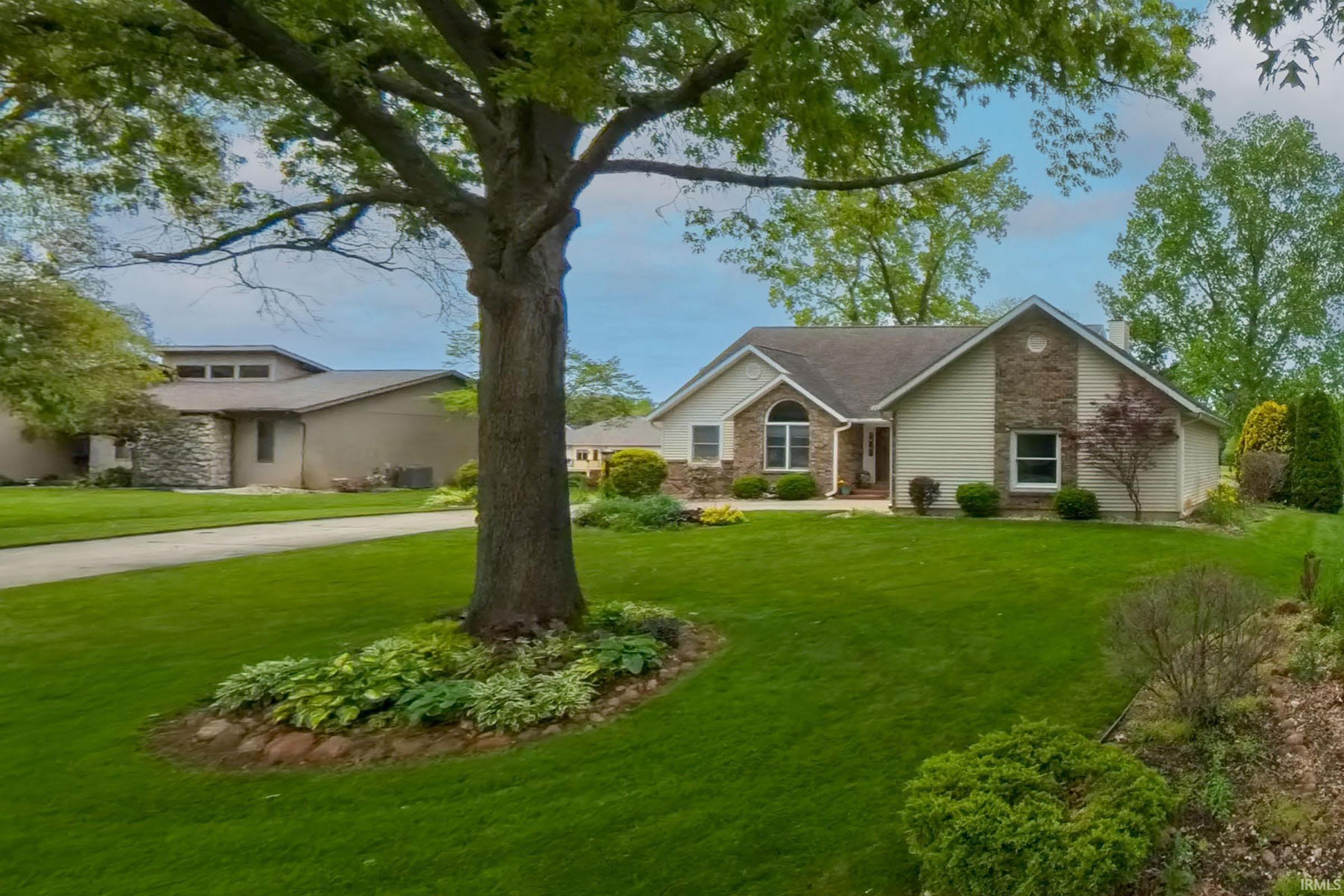 Front exterior featuring a combination of stone and siding finishes, a multi-pane arched window, and an integrated garage