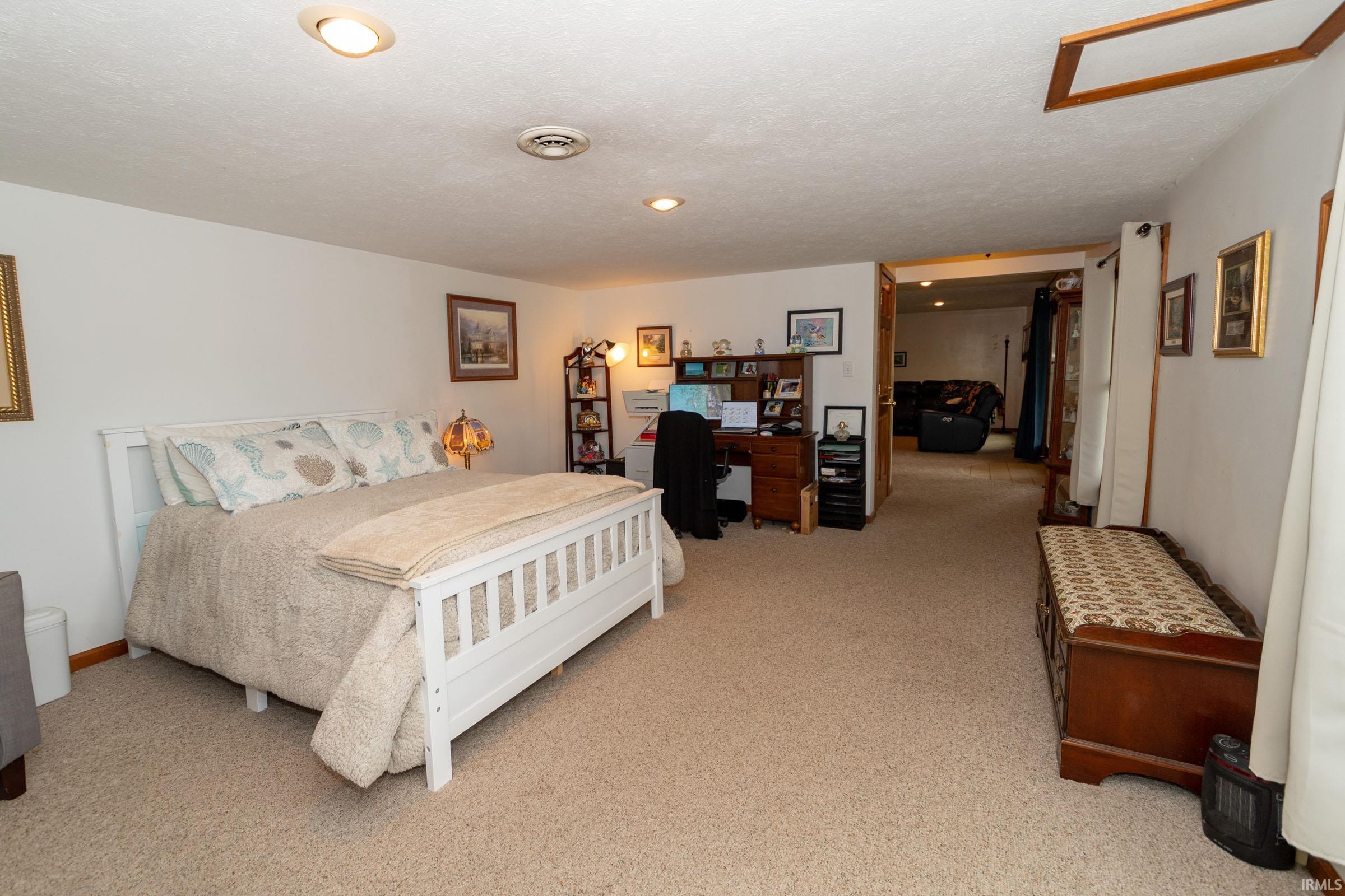 Carpeted room featuring recessed lighting, white walls, and a wooden bed frame