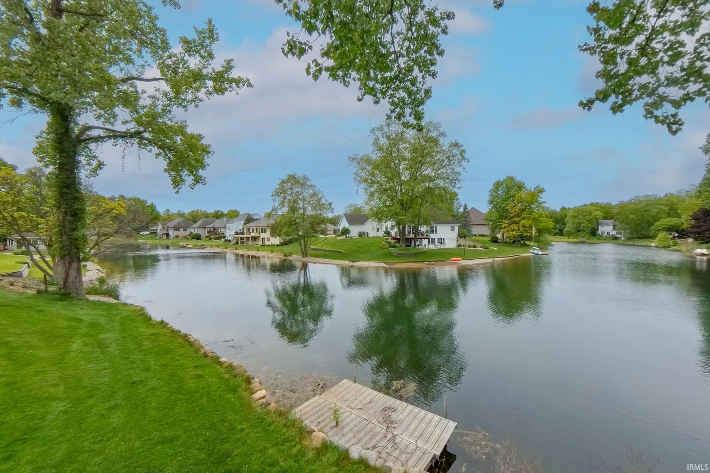 Lakeside frontage featuring a private dock and lush green lawn