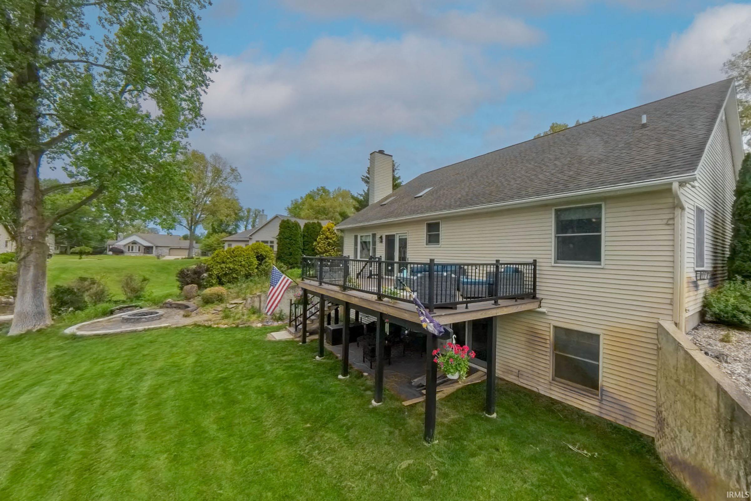 Rear exterior featuring a multi-level deck, a lower-level patio, and a dedicated fire pit area