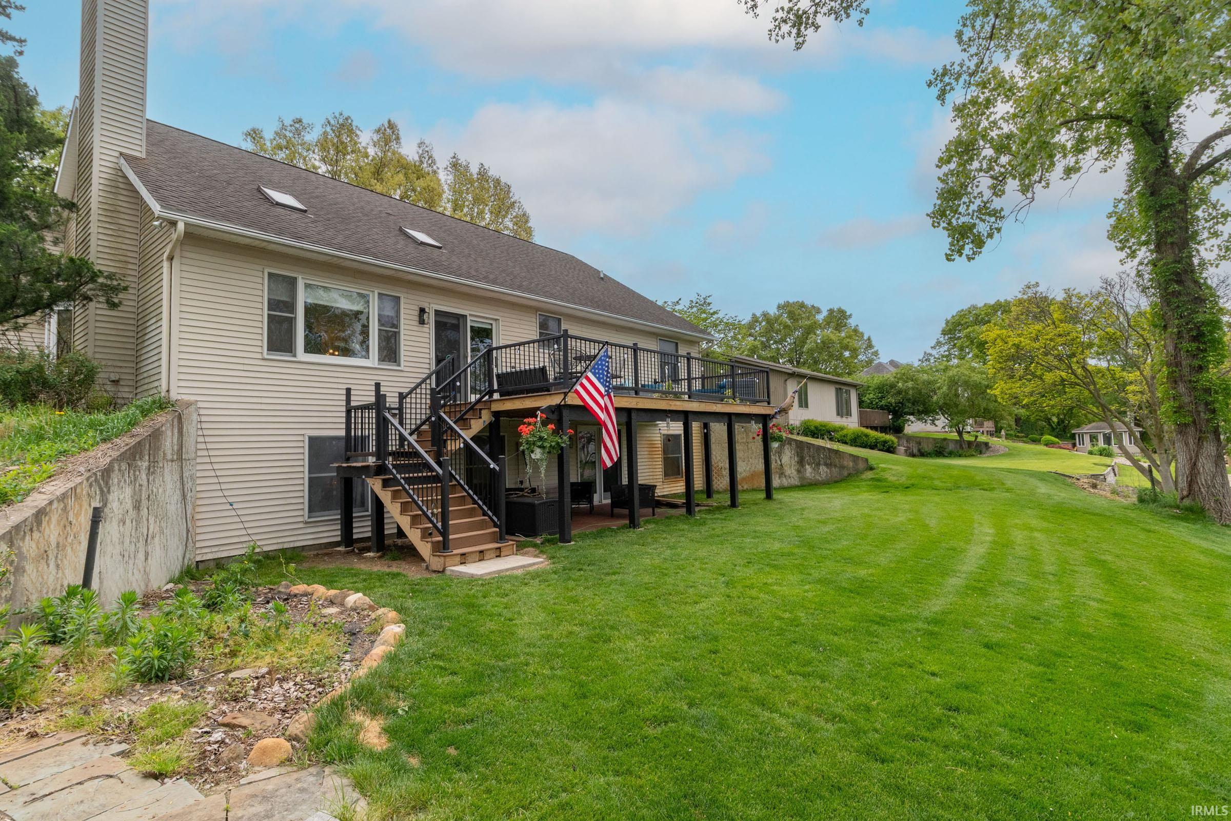 Expansive backyard featuring a manicured lawn, multi-level deck with black railings, and a walk-out lower level