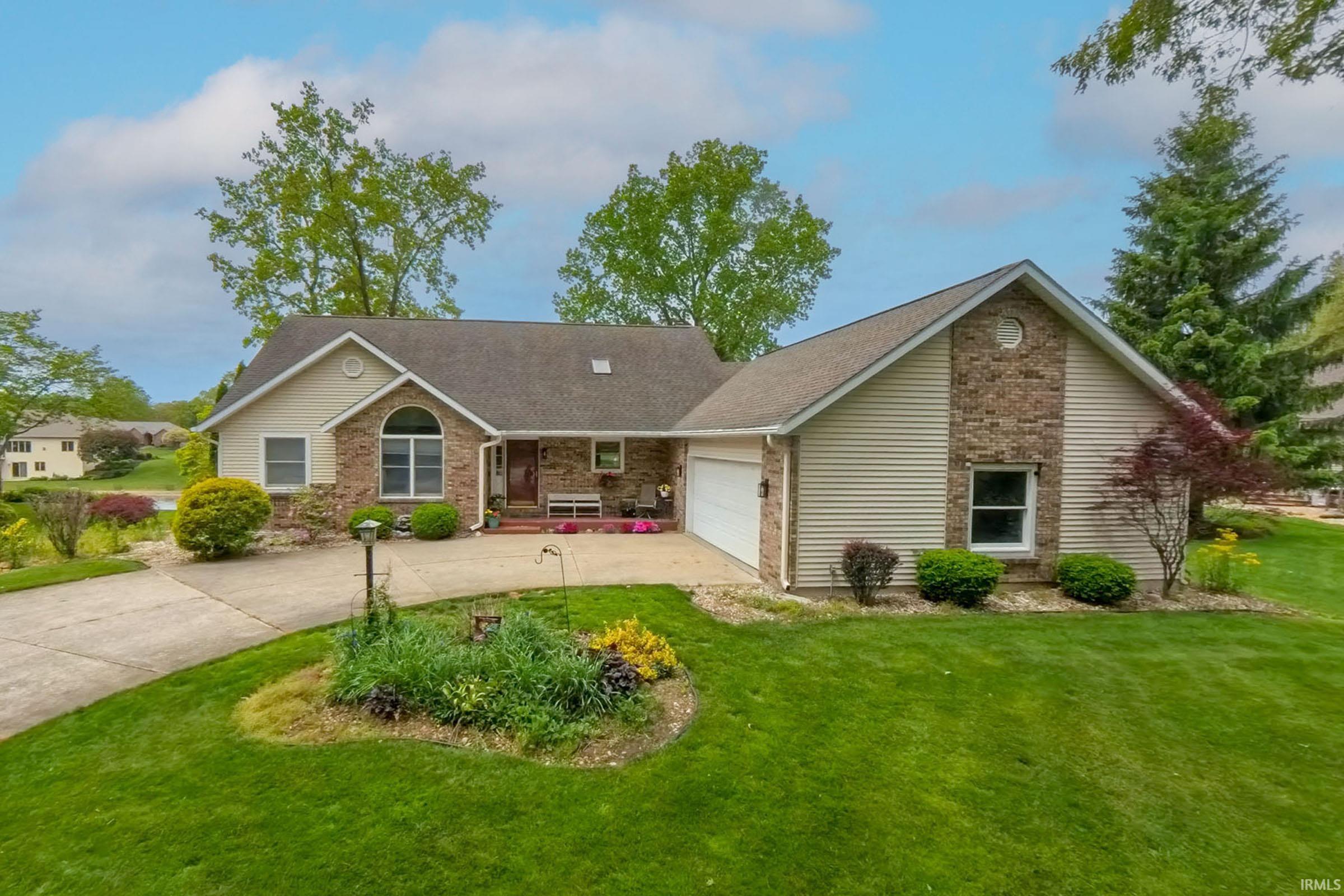 Ranch-style residence featuring a prominent two-car garage, concrete driveway, and established green lawn