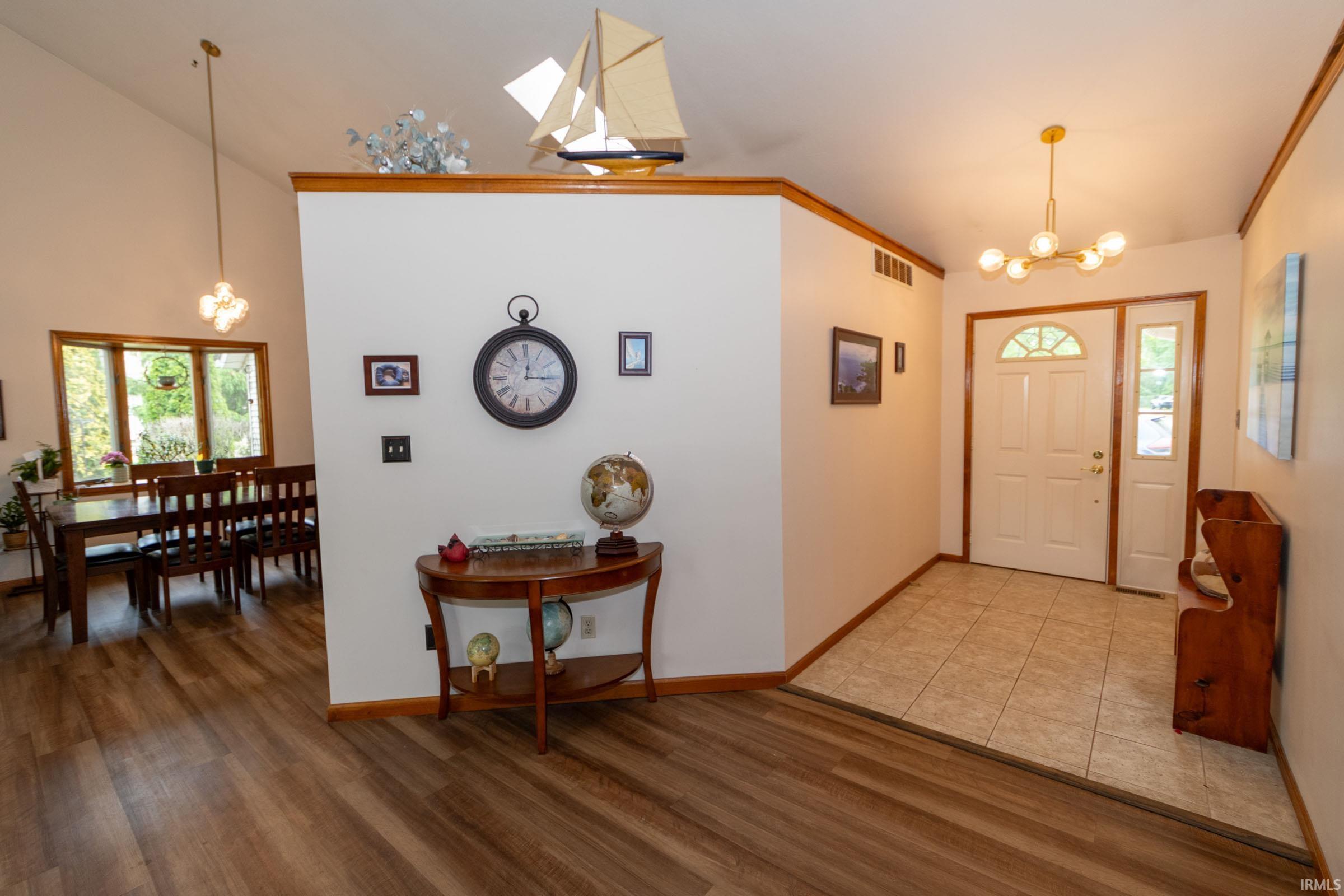 Entryway featuring a white paneled door with an arched transom, a sidelight, and a modern gold-finish chandelier