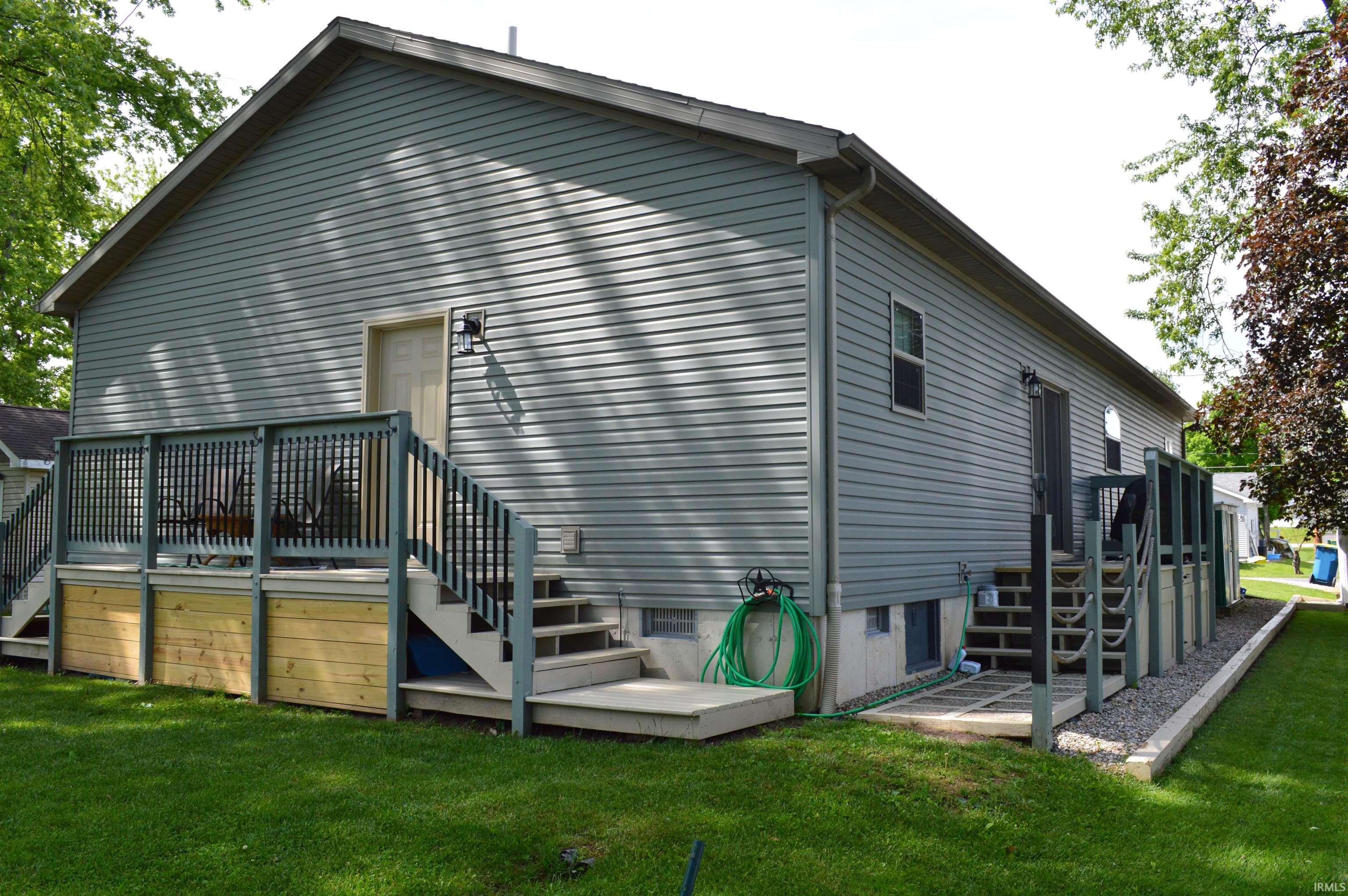 Rear exterior featuring light grey siding, a gabled roofline, and multiple outdoor access points