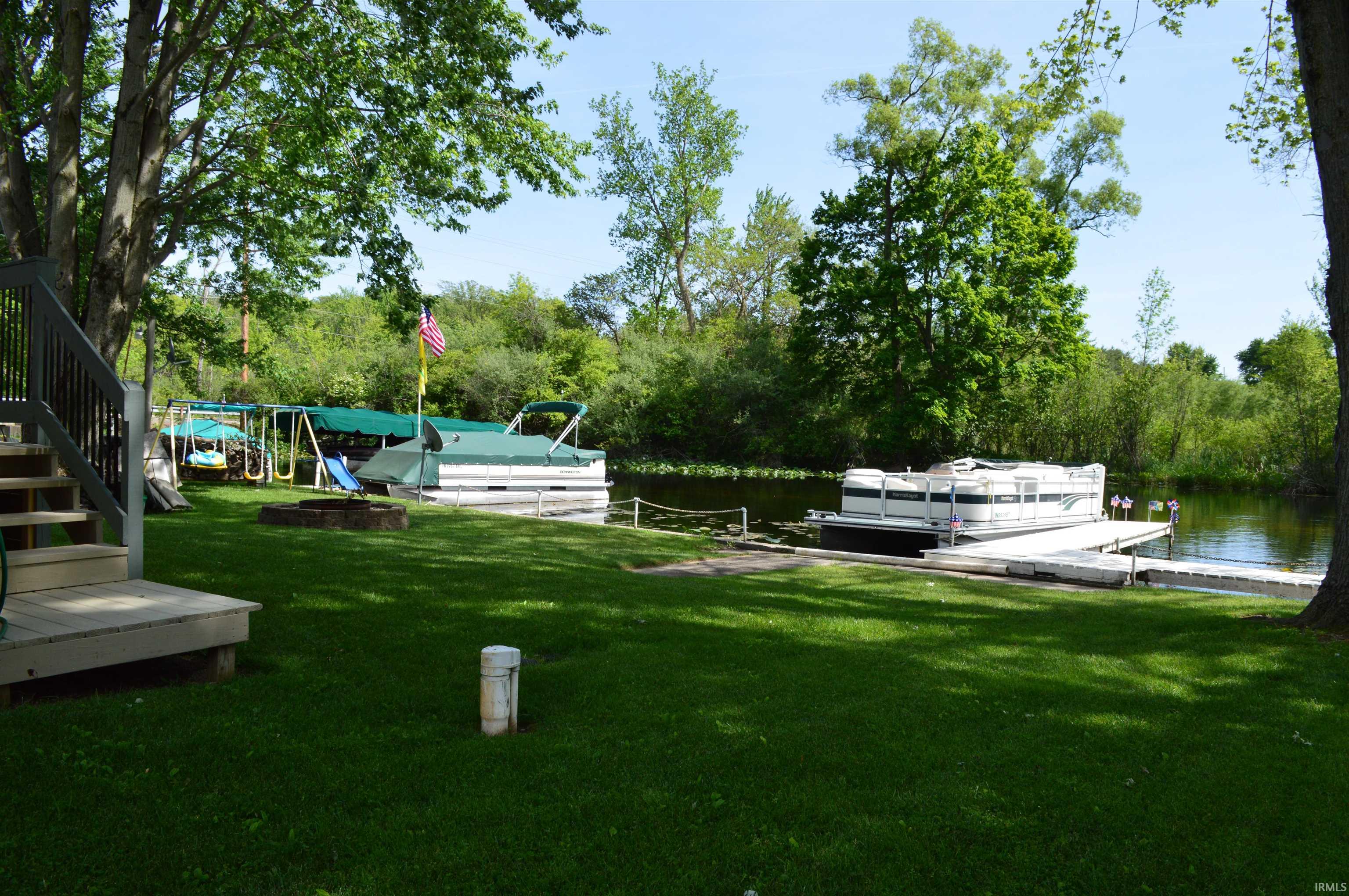 Waterfront property featuring a manicured lawn, dedicated boat docks, and mature trees