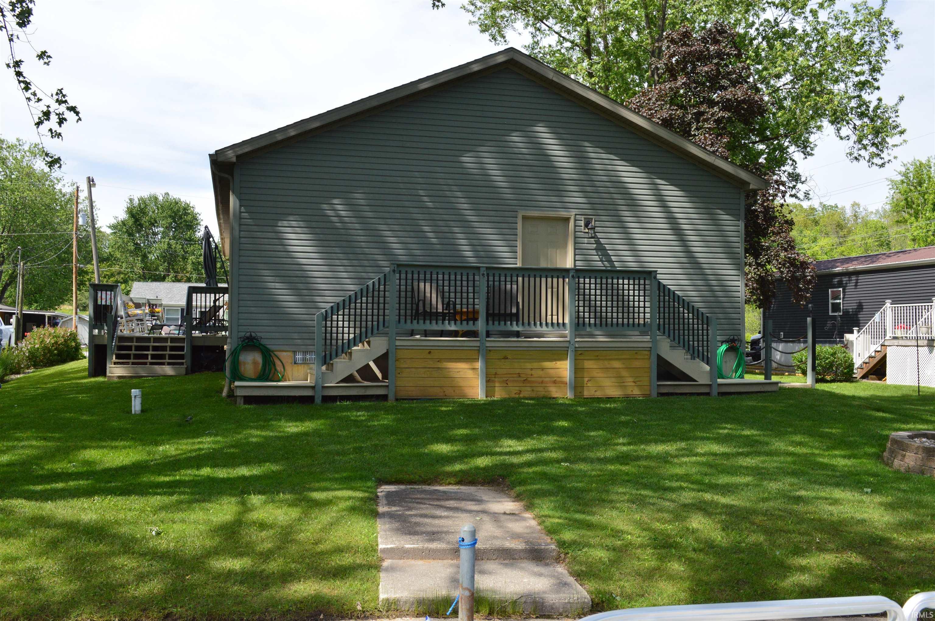 Rear exterior featuring horizontal siding, a multi-level deck with railings, and a concrete path
