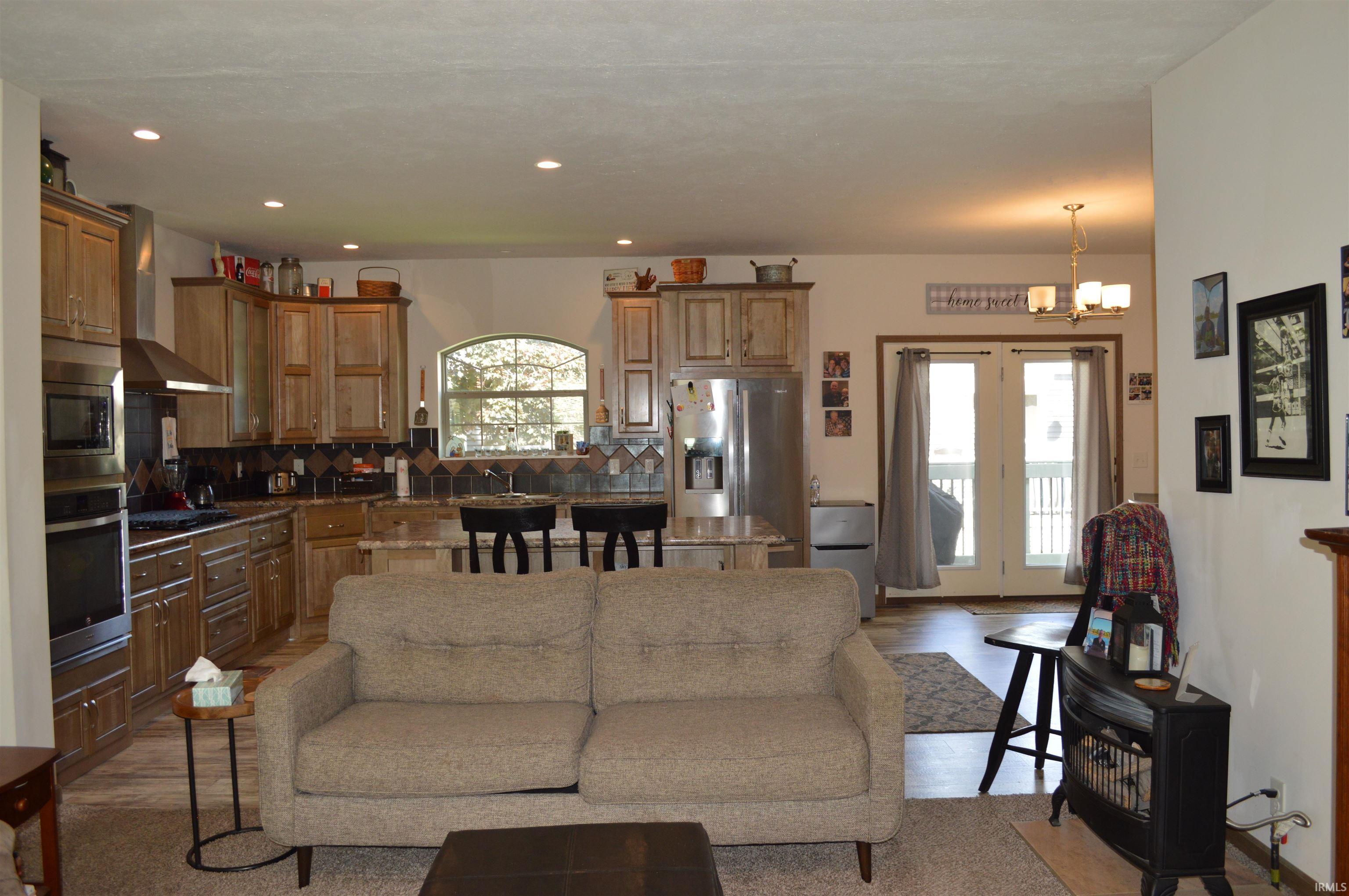 Open-concept living space featuring a kitchen with light wood cabinetry, stainless steel appliances, and a built-in oven